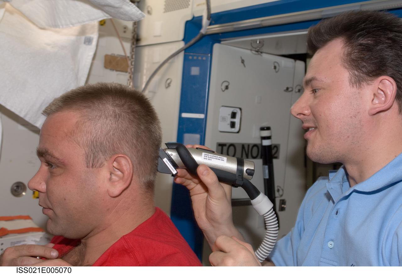 ISS021-E-005070 (11 Oct. 2009) --- Russian cosmonaut Roman Romanenko, Expedition 21 flight engineer, trims Russian cosmonaut Maxim Suraev's hair in the Destiny laboratory of the International Space Station. Romanenko used hair clippers fashioned with a vacuum device to garner freshly cut hair.