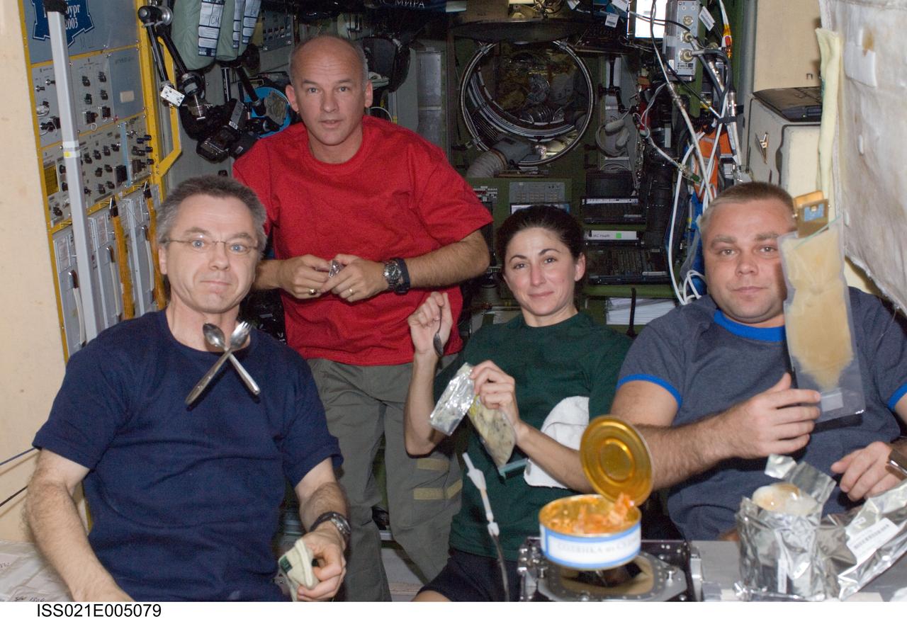 ISS021-E-005079 (12 Oct. 2009) --- Canadian Space Agency astronaut Robert Thirsk (left), NASA astronauts Jeffrey Williams and Nicole Stott; along with Russian cosmonaut Maxim Suraev, all Expedition 21 flight engineers, share a meal at the galley in the Zvezda Service Module of the International Space Station.