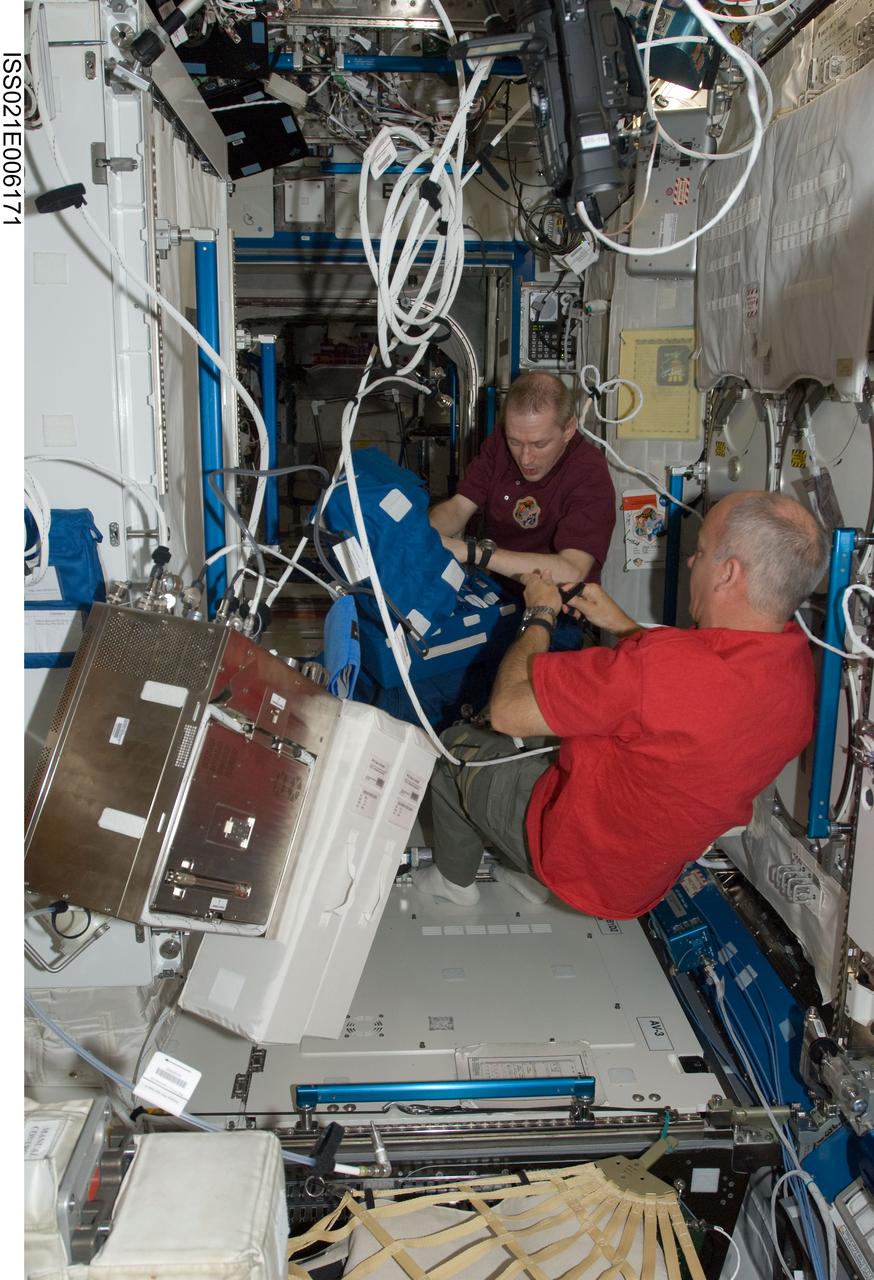 ISS021-E-006171 (14 Oct. 2009) --- European Space Agency astronaut Frank De Winne (background), Expedition 21 commander; and NASA astronaut Jeffrey Williams, flight engineer, work in the Destiny laboratory of the International Space Station.