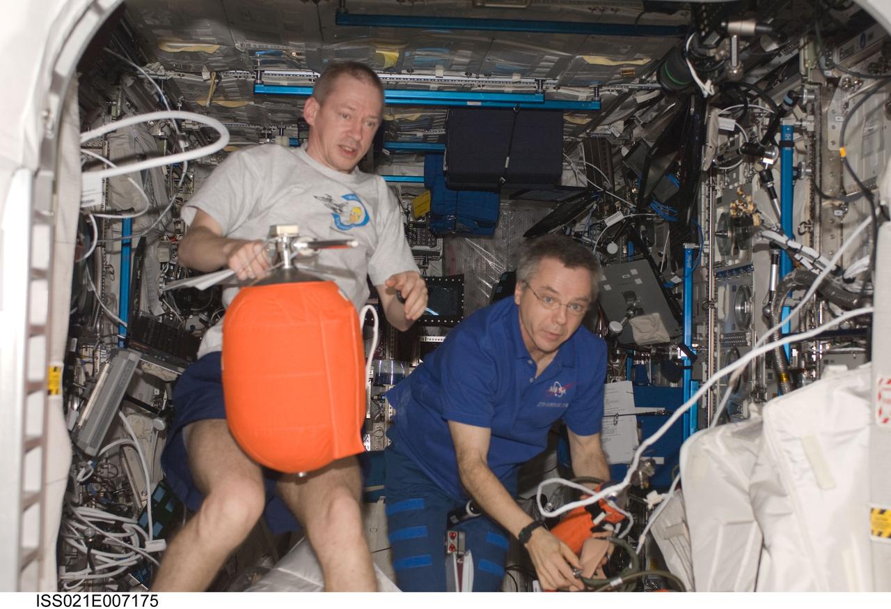 ISS021-E-007175 (15 Oct. 2009) --- European Space Agency astronaut Frank De Winne (left), Expedition 21 commander; and Canadian Space Agency astronaut Robert Thirsk, flight engineer, conduct an onboard training (OBT) fire drill in the Columbus laboratory of the International Space Station.