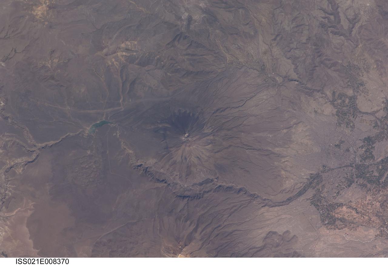ISS021-E-008370 (16 Oct. 2009) --- El Misti volcano in Peru is featured in this image photographed by an Expedition 21 crew member on the International Space Station. The symmetric conical shape of El Misti is typical of a stratovolcano ? a type of volcano characterized by interlayered lavas and products of explosive eruptions, such as ash and pyroclastic flow deposits. Stratovolcanoes are usually located on the continental crust above a subducting tectonic plate. Magma feeding the stratovolcanoes of the Andes Mountains ? including 5,822 meter-high El Misti ? is associated with ongoing subduction of the Nazca Plate beneath the South American Plate. El Misti?s most recent -- and relatively minor -- eruption occurred in 1985. The city center of Arequipa, Peru lies only 17 kilometers away from the summit of El Misti; the gray urban area is bordered by green agricultural fields (right). With almost one million residents in 2009, it is the second city of Peru in terms of population. Much of the building stone for Arequipa, known locally as sillar, is quarried from nearby pyroclastic flow deposits that are white in color. Arequipa is known as ?the White City? because of the prevalence of this building material. The Chili River extends northeastwards from the city center, and flows through a canyon (left) between El Misti volcano and Nevado Chachani to the north.