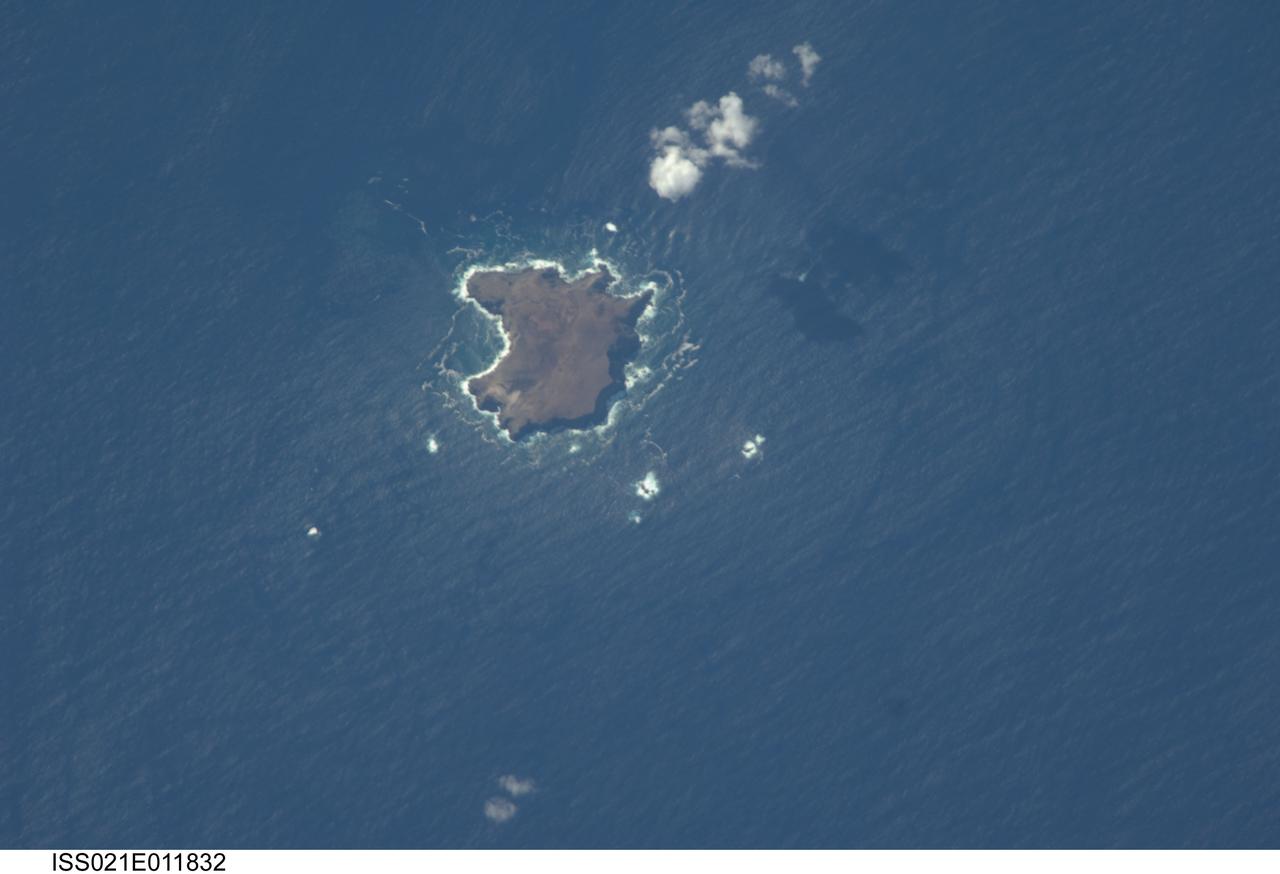 ISS021-E-011832 (22 Oct. 2009) --- The northern Savage Islands in the Atlantic Ocean are featured in this image photographed by an Expedition 21 crew member on the International Space Station. The Savage Islands, or Ilhas Selvagens in Portuguese, comprise a small archipelago in the eastern North Atlantic Ocean between the archipelago of Madeira to the north and the Canary Islands to the south. Like other island groups, the Savage Islands are thought to have been produced by volcanism related to a mantle plume or “hot spot”. Mantle plumes are relatively fixed regions of upwelling magma that can feed volcanoes on an overlying tectonic plate. Active volcanoes form over the plume, and become dormant as they are carried away on the moving tectonic plate. Scientists believe that over geologic time, this creates a line of older extinct volcanoes, seamounts, and islands extending from the leading active volcanoes that are currently over the plume. This view illustrates Selvagem Grande, the largest of the islands with an approximate area of four square kilometers. All of the islands of the archipelago are ringed by bright white breaking waves along the fringing beaches. Coral reefs that surround the Savage Islands make it very difficult to land boats there, and there is no permanent settlement on the islands.