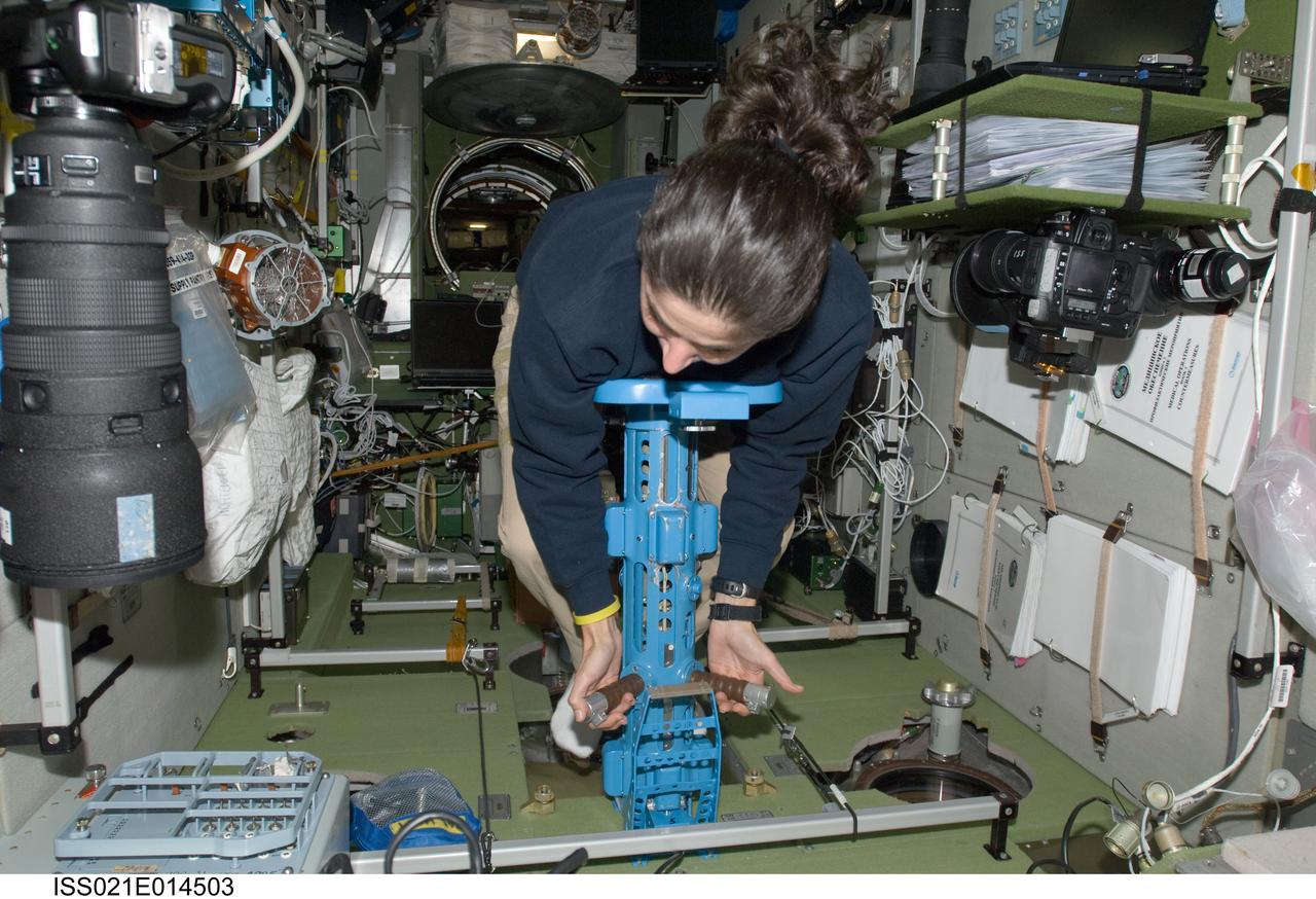 ISS021-E-014503 (12 Oct. 2009) --- NASA astronaut Nicole Stott, Expedition 21 flight engineer, uses the IM mass measurement device to perform the PZEh-MO-8/Body Mass Measurement Russian biomedical routine assessments in the Zvezda Service Module of the International Space Station.