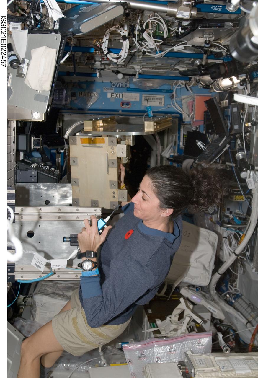ISS021-E-022457 (9 Nov. 2009) --- NASA astronaut Nicole Stott, Expedition 21 flight engineer, uses a communication system while installing the Light Microscopy Module (LMM) Spindle Bracket Assembly in the Fluids Integrated Rack (FIR) in the Destiny laboratory of the International Space Station. Canadian Space Agency astronaut Robert Thirsk (out of frame) assisted Stott.
