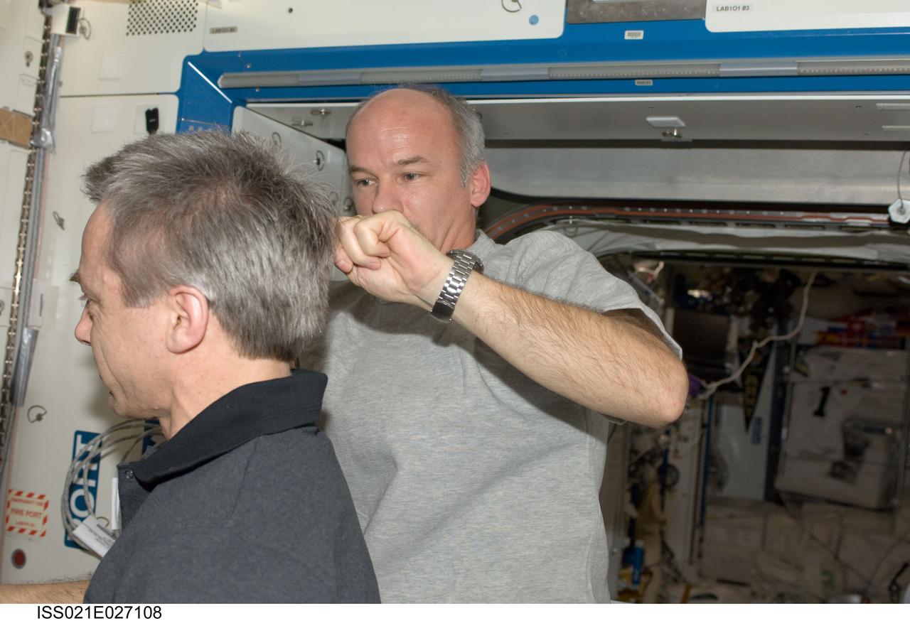 ISS021-E-027108 (15 Nov. 2009) --- NASA astronaut Jeffrey Williams, Expedition 21 flight engineer, trims Canadian Space Agency astronaut Robert Thirsk's hair in the Destiny laboratory of the International Space Station. Williams used hair clippers fashioned with a vacuum device to garner freshly cut hair.