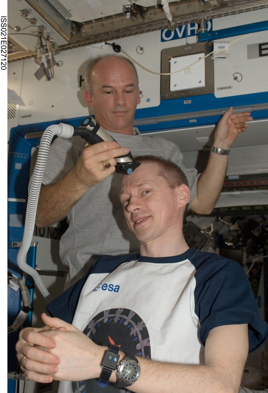 ISS021-E-027120 (15 Nov. 2009) --- NASA astronaut Jeffrey Williams, Expedition 21 flight engineer, trims European Space Agency astronaut Frank De Winne's hair in the Destiny laboratory of the International Space Station. Williams used hair clippers fashioned with a vacuum device to garner freshly cut hair.