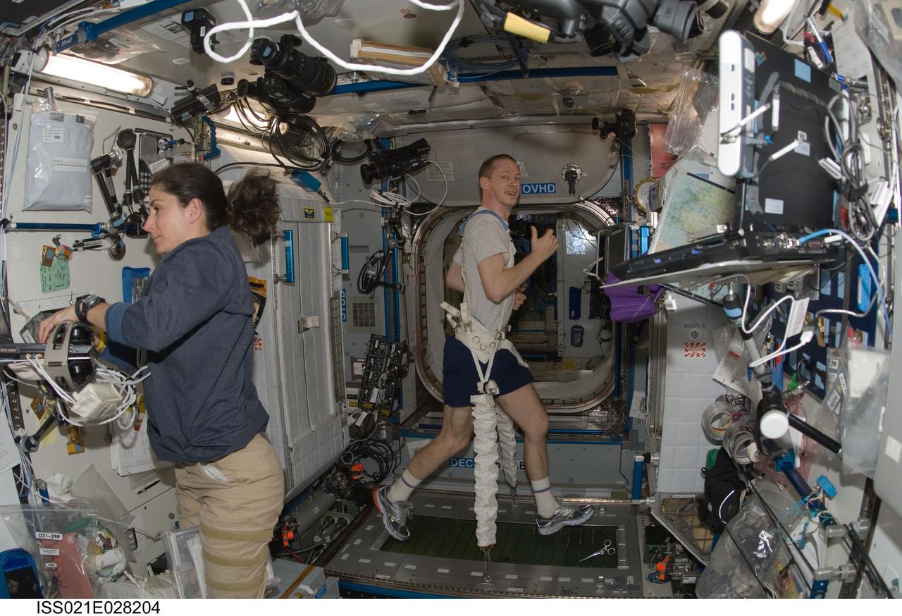 ISS021-E-028204 (17 Nov. 2009) --- European Space Agency astronaut Frank De Winne, Expedition 21 commander, exercises on the Combined Operational Load Bearing External Resistance Treadmill (COLBERT) in the Harmony node of the International Space Station. NASA astronaut Nicole Stott, flight engineer, works at left.