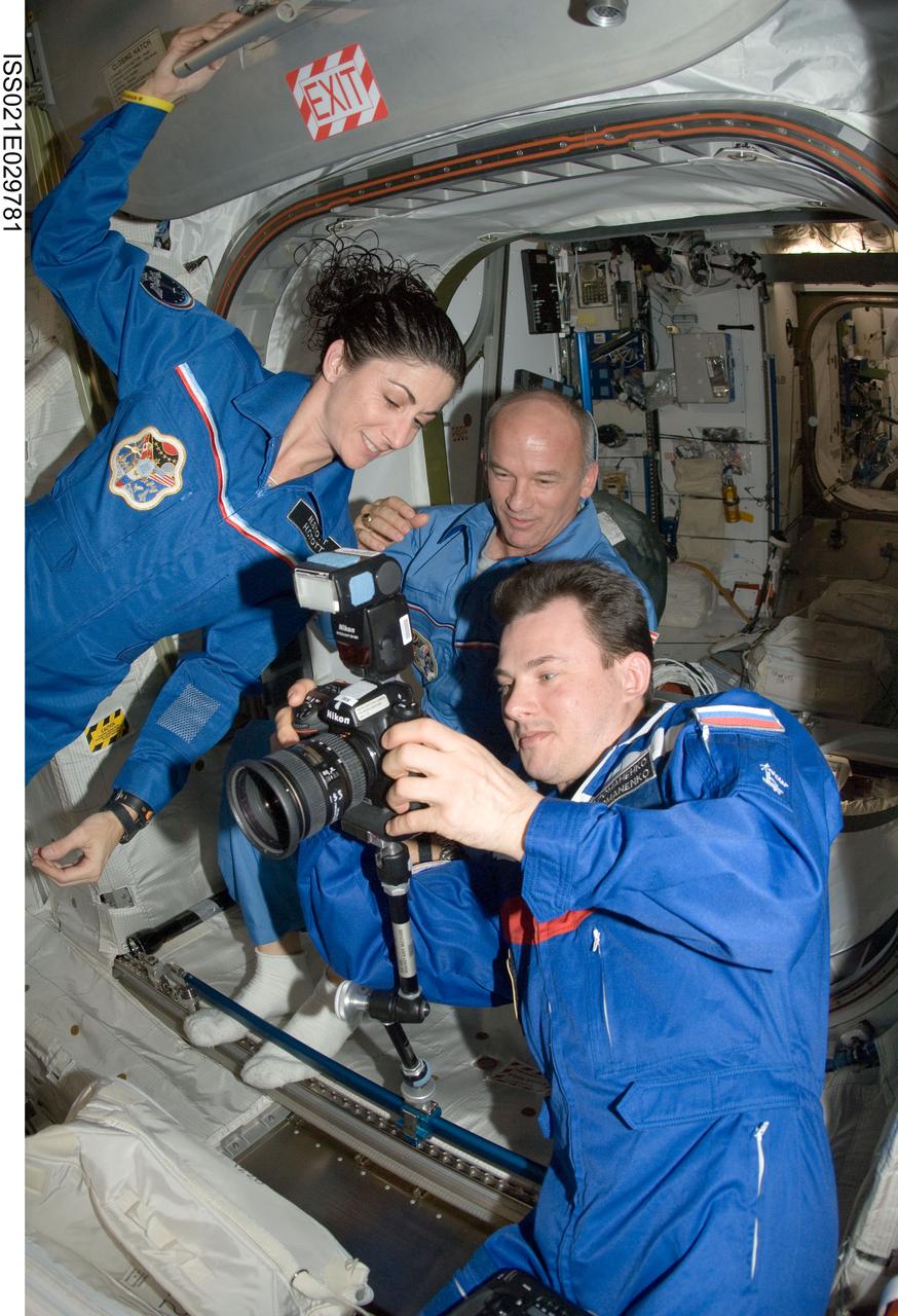 ISS021-E-029781 (17 Nov. 2009) --- Russian cosmonaut Roman Romanenko, Expedition 21 flight engineer, uses a still camera in the Columbus laboratory of the International Space Station while NASA astronauts Nicole Stott and Jeffrey Williams, both flight engineers, look on.