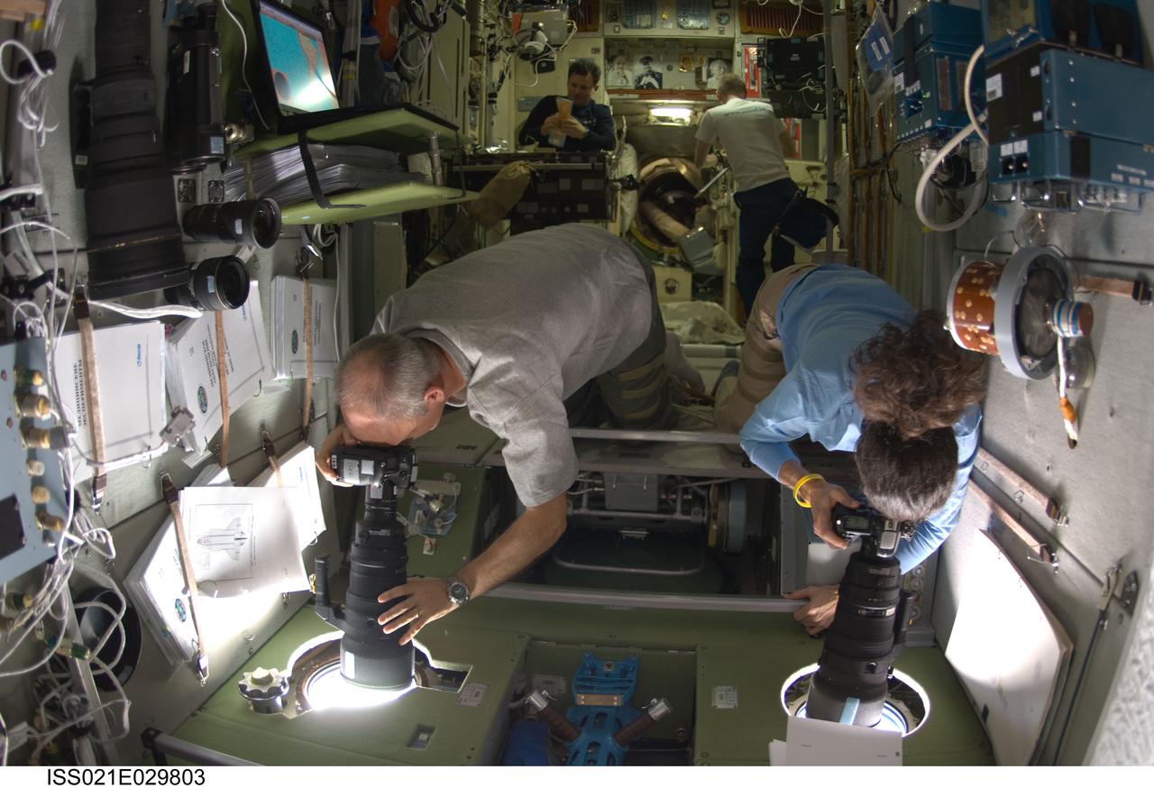 ISS021-E-029803 (18 Nov. 2009) --- NASA astronauts Jeffrey Williams and Nicole Stott, both Expedition 21 flight engineers, use still cameras at windows in the Zvezda Service Module of the International Space as Space Shuttle Atlantis approaches the station.