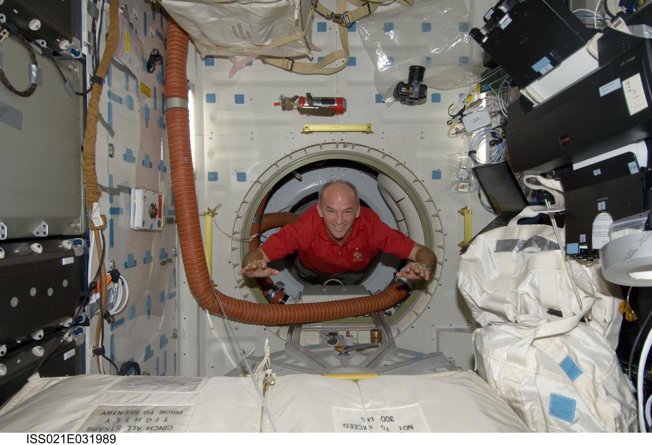 ISS021-E-031989 (23 Nov. 2009) --- Astronaut Jeffrey Williams, Expedition 21 flight engineer, floats through a hatch onto the middeck of space shuttle Atlantis (STS-129) while docked with the International Space Station.