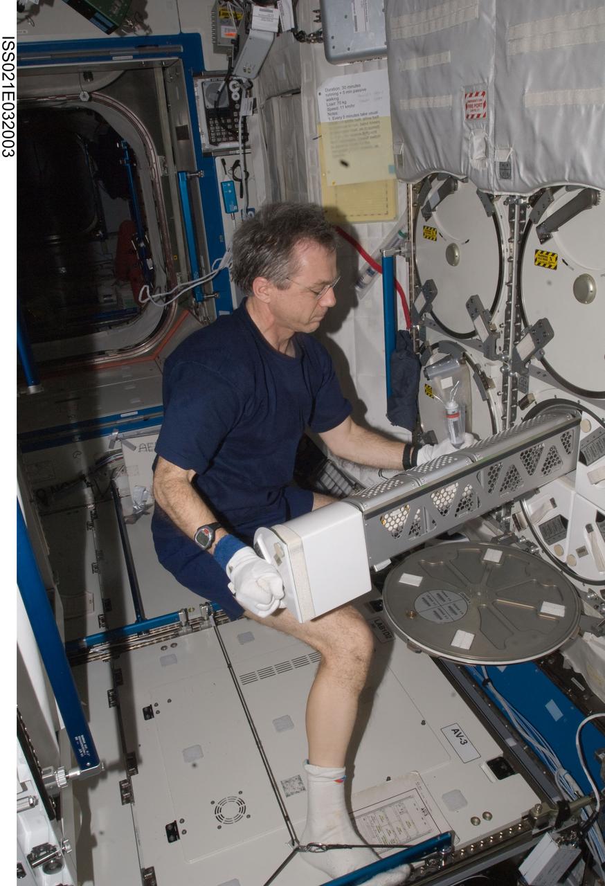 ISS021-E-032003 (22 Nov. 2009) --- Canadian Space Agency astronaut Robert Thirsk, Expedition 21 flight engineer, removes a dewar tray from the Minus Eighty Laboratory Freezer for ISS (MELFI) in the Destiny laboratory of the International Space Station while space shuttle Atlantis (STS-129) remains docked with the station.
