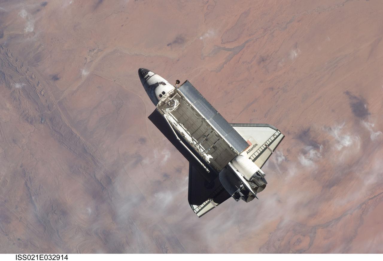 ISS021-E-032914 (25 Nov. 2009) --- Backdropped by a colorful part of Earth, space shuttle Atlantis (STS-129) is featured in this image photographed by an Expedition 21 crew member on the International Space Station soon after the shuttle and station began their post-undocking relative separation. Undocking of the two spacecraft occurred at 3:53 a.m. (CST) on Nov. 25, 2009.