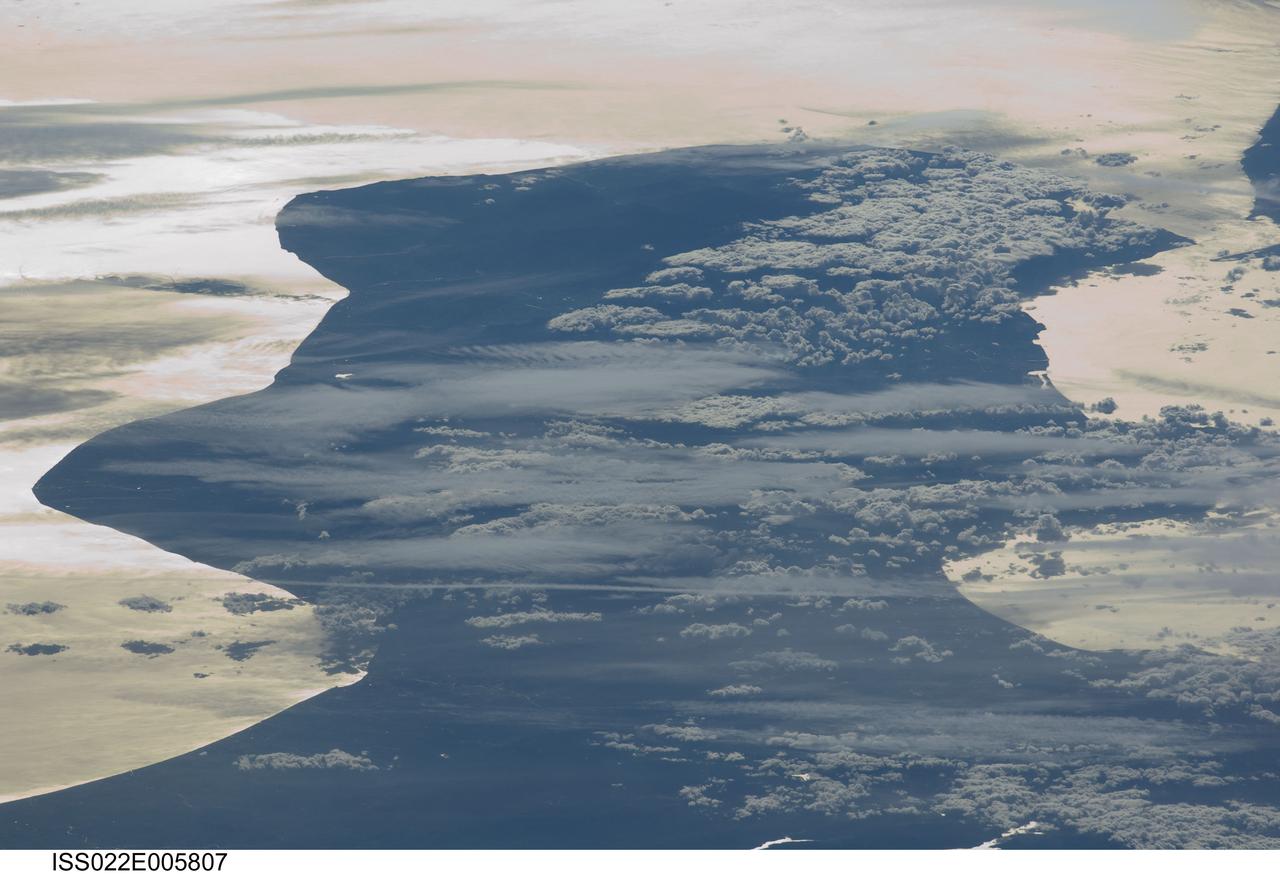 ISS022-E-005807 (3 Dec. 2009) --- Cloud formations and sunglint near Italy are featured in this image photographed by an Expedition 22 crew member on the International Space Station. This view depicts the Calabria region of southern Italy ? the toe of Italy?s ?boot? ? outlined by the Ionian and Tyrrhenian Seas to the southeast and northwest respectively. The water surfaces present a mirror-like appearance due to sunglint. This phenomenon is caused by sunlight reflecting off the water surface directly back towards the crew member aboard the space station. The ISS was located over northwestern Romania, approximately 1,040 kilometers to the northeast of Calabria, when this image was taken. The Calabrian peninsula appears shortened and distorted due to the high viewing angle from the station. Such imagery is termed oblique, indicating that the view is not looking directly downwards towards Earth?s surface from the ISS (known as a nadir view). This highly oblique view also highlights two distinct cloud patterns over the Calabrian interior. Patchy, highly textured cumulus clouds are present at lower altitudes, while grey altostratus clouds are elongated by prevailing winds at higher altitudes. The Strait of Messina, just visible at upper right, marks the boundary between the coastlines of Italy and the island of Sicily.