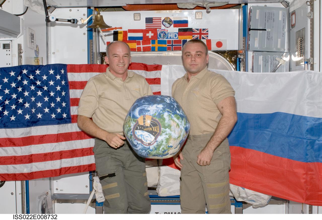 ISS022-E-008732 (13 Dec. 2009) --- NASA astronaut Jeffrey Williams (left), Expedition 22 commander; and Russian cosmonaut Maxim Suraev, flight engineer, hold a globe with the Expedition 22 logo during a segment of Rusalka video footage as part of Suraev?s "Live on ISS" program for the Russian Channel TVTs, via US assets (S-band & Ku-band). The event took place in the Harmony node of the International Space Station.