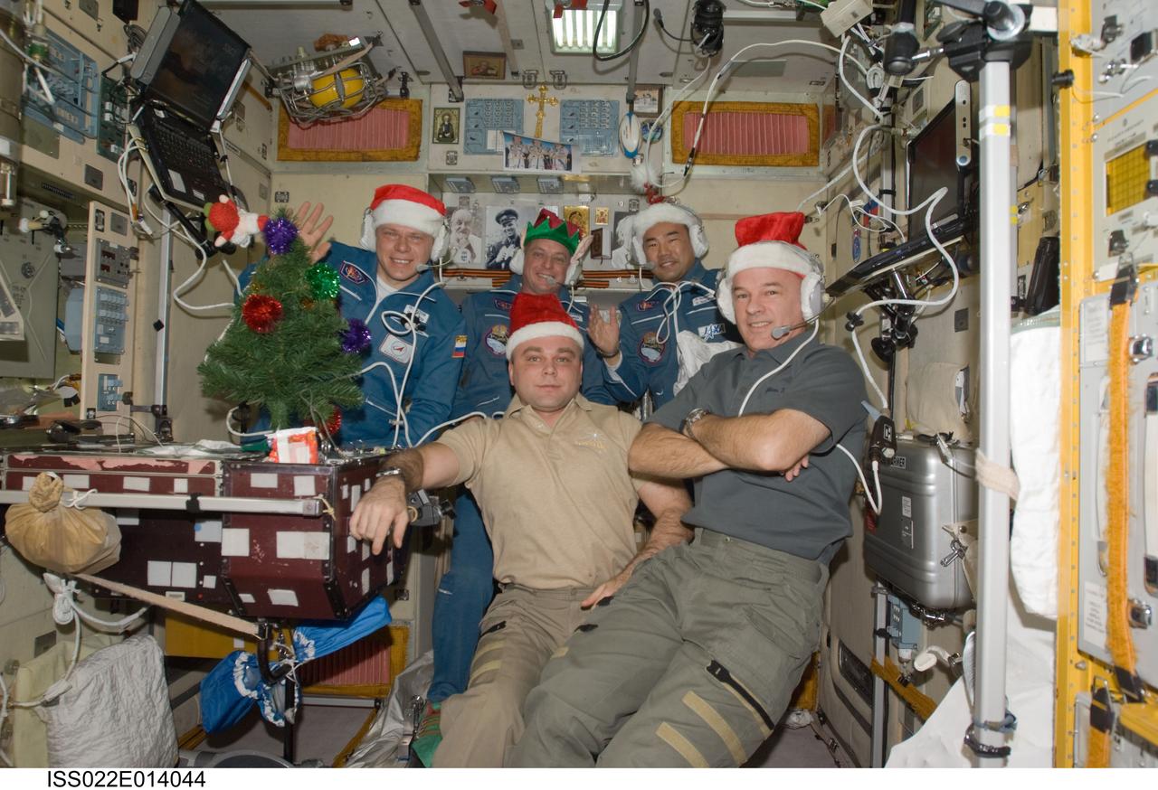 ISS022-E-014044 (22 Dec. 2009) --- Wearing festive holiday hats, the Expedition 22 crew members are pictured while speaking with officials from Russia, Japan and the United States from the Zvezda Service Module of the International Space Station. In the front row, are NASA astronaut Jeffrey Williams (right), commander; and Russian cosmonaut Maxim Suraev, flight engineer. Pictured on the back row (left to right) are Russian cosmonaut Oleg Kotov, NASA astronaut T.J. Creamer and Japan Aerospace Exploration Agency astronaut Soichi Noguchi, all flight engineers.