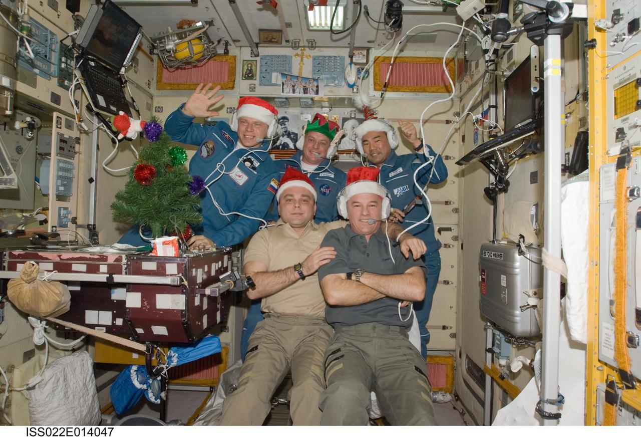 ISS022-E-014047 (22 Dec. 2009) --- Wearing festive holiday hats, the Expedition 22 crew members are pictured while speaking with officials from Russia, Japan and the United States from the Zvezda Service Module of the International Space Station. In the front row, are NASA astronaut Jeffrey Williams (right), commander; and Russian cosmonaut Maxim Suraev, flight engineer. Pictured on the back row (left to right) are Russian cosmonaut Oleg Kotov, NASA astronaut T.J. Creamer and Japan Aerospace Exploration Agency astronaut Soichi Noguchi, all flight engineers.