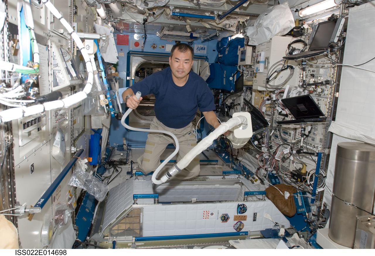 ISS022-E-014698 (26 Dec. 2009) --- Japan Aerospace Exploration Agency astronaut Soichi Noguchi, Expedition 22 flight engineer, uses a vacuum cleaner during housekeeping operations in the Kibo laboratory of the International Space Station.