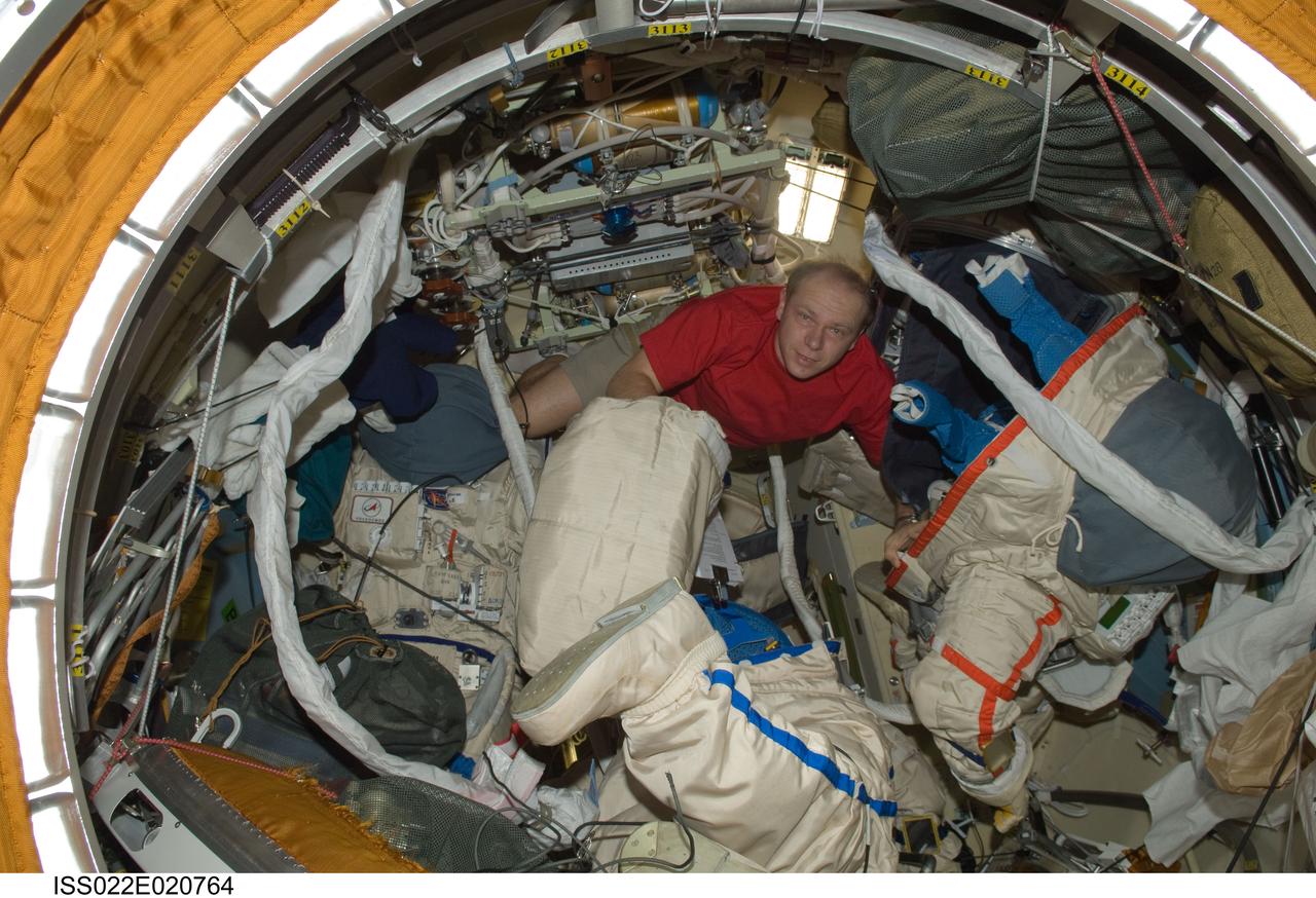 ISS022-E-020764 (7 Jan. 2010) --- Russian cosmonaut Oleg Kotov, Expedition 22 flight engineer, works with extravehicular activity (EVA) equipment and Russian Orlan spacesuits in the Pirs Docking Compartment of the International Space Station.