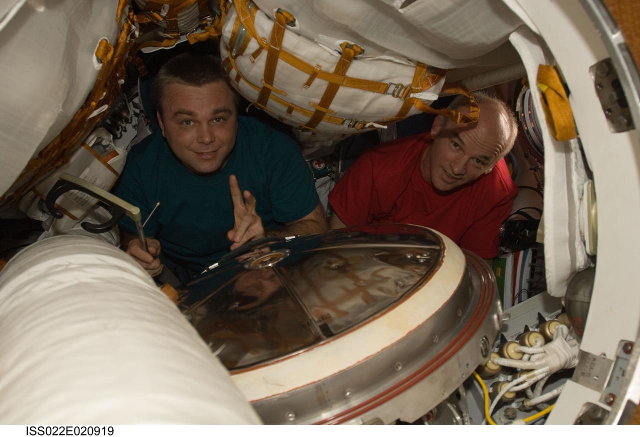 ISS022-E-020919 (8 Jan. 2010) --- NASA astronaut Jeffrey Williams (right), Expedition 22 commander; and Russian cosmonaut Maxim Suraev, flight engineer, are pictured in a Russian Soyuz spacecraft docked with the International Space Station. The crew conducted comprehensive leak checks on the two Soyuz vehicles and the Progress cargo craft docked to the space station.