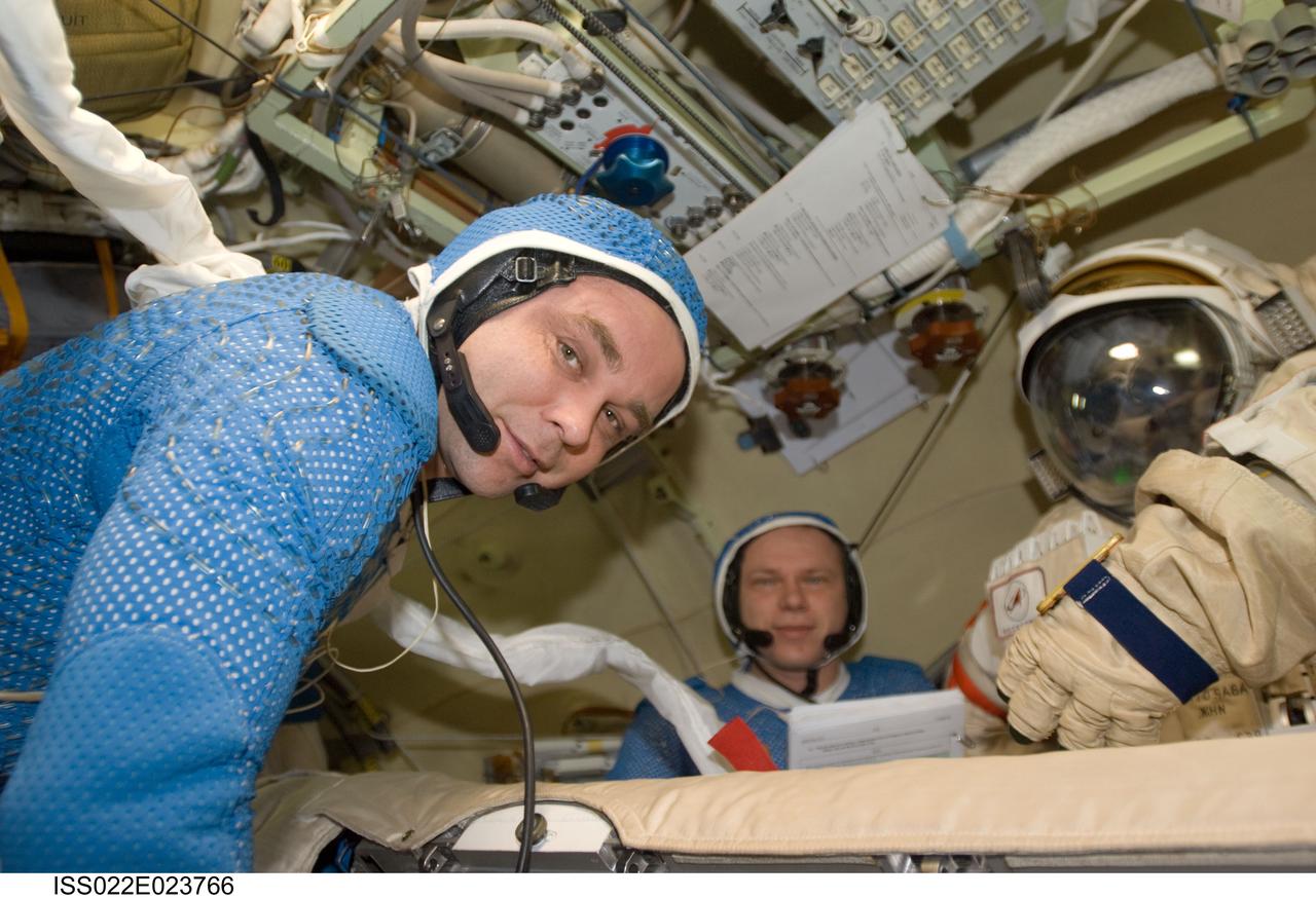 ISS022-E-023766 (12 Jan. 2010) --- Attired in blue thermal undergarments that complement the Russian Orlan spacesuit, Russian cosmonauts Maxim Suraev (foreground) and Oleg Kotov, both Expedition 22 flight engineers, prepare to don and check out their Orlan spacesuits in preparation for a spacewalk scheduled for Jan. 14 to outfit the new Poisk module for future Russian vehicle dockings.