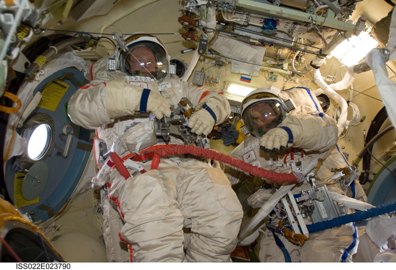 ISS022-E-023790 (12 Jan. 2010) --- Attired in their Russian Orlan spacesuits, Russian cosmonauts Oleg Kotov (left) and Maxim Suraev, both Expedition 22 flight engineers, check out their Orlan suits in preparation for a spacewalk scheduled for Jan. 14 to outfit the new Poisk module for future Russian vehicle dockings.
