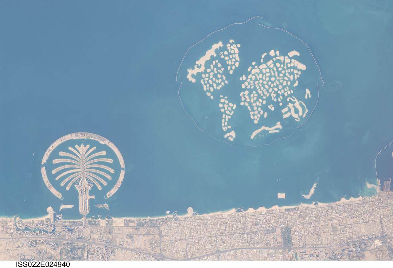 ISS022-E-024940 (13 Jan. 2010) --- Man-made archipelagos near Dubai, United Arab Emirates are featured in this image photographed by an Expedition 22 crew member on the International Space Station. The municipality of Dubai is the largest city of the Persian Gulf emirate of the same name, and has built a global reputation for large-scale developments and architectural works. Among the most visible of these developments ? particularly from the perspective of astronauts onboard the ISS ? are three man-made archipelagos. The two Palm Islands (Palm Jumeirah and Palm Jebel Ali) appear as stylized palm trees when viewed from above. The World Islands evoke a rough map of the world from an air- or space-borne perspective.  Palm Jumeirah and the World Islands are highlighted in this view. Palm Jumeirah (lower left) was begun in 2001 and required more than 50 million cubic meters of dredged sand to raise the islands above the Persian Gulf sea level. Construction of the Palm Jumeirah islands was completed in 2006; they are now being developed for residential and commercial housing and infrastructure. Creation of the 300 World Islands (upper right) was begun in 2003 and completed in 2008, using 320 million cubic meters of sand and 37 million tons of rock for the surrounding 27 kilometer-long protective breakwater. Also visible at the lower edge of the image is another notable built structure ? the Burj Tower (white rectangle at lower right and inset image). The Burj Tower ? or Burj Khalifa ? stands 800 meters high, and is currently the world?s tallest structure. The photograph captures enough detail to make out the tapering outline of the building as well as its dark needle-like shadow pointing towards the northeast.