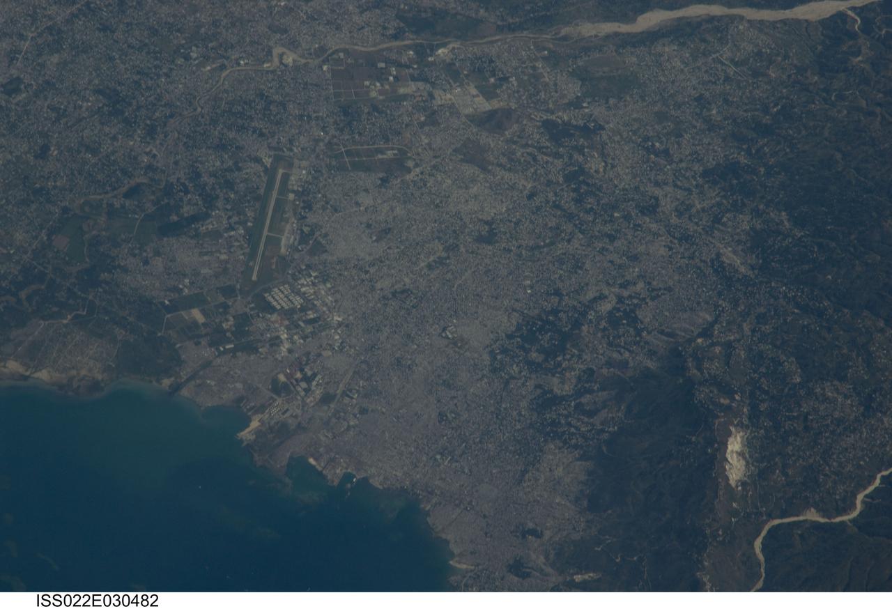 ISS022-E-030482 (18 Jan. 2010) --? An Expedition 22 crew member onboard the International Space Station took this image of the 260 year old city, Port-au-Prince on Jan. 18, 2010 when they could view the area. This was a few days after the major Haitian earthquake occurred and brought devastation to Port-au-Prince, Carrefour, and the surrounding region. The  Toussaint Louverture International Airport, clearly visible on the north side of Port-au-Prince, is the central focal point of incoming international aid.  The population of Port-au-Prince is estimated to be between 2.5 to 3 million people. The photo was taken with an 800 mm lens setting.