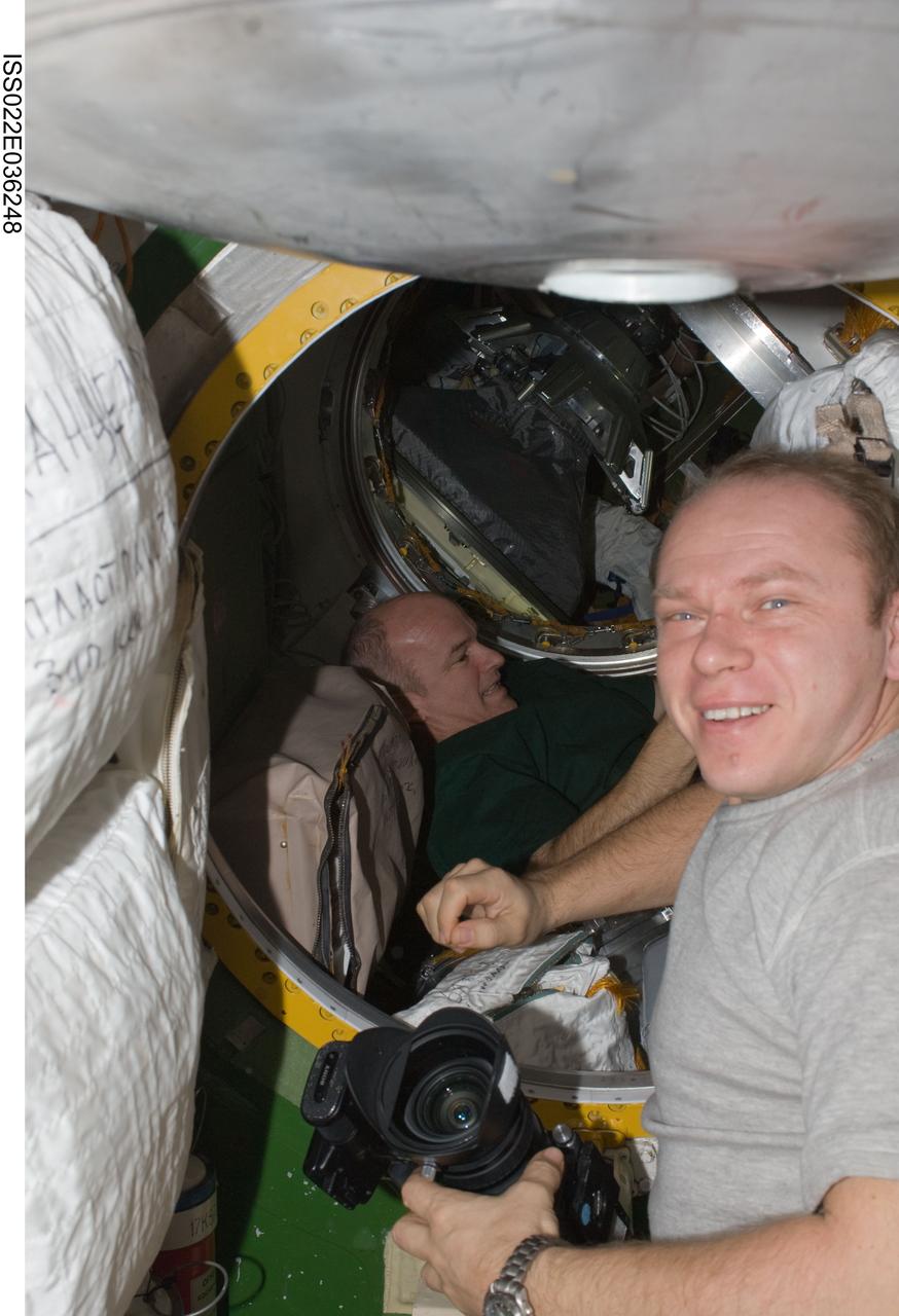 ISS022-E-036248 (21 Jan. 2010) --- Russian cosmonaut Oleg Kotov, Expedition 22 flight engineer; and NASA astronaut Jeffrey Williams (background), commander, work in the Pirs Docking Compartment of the International Space Station.