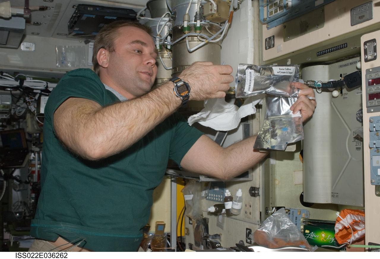 ISS022-E-036262 (21 Jan. 2010) --- Russian cosmonaut Maxim Suraev, Expedition 22 flight engineer, adds potable water to a soft beverage container at the galley in the Zvezda Service Module of the International Space Station.