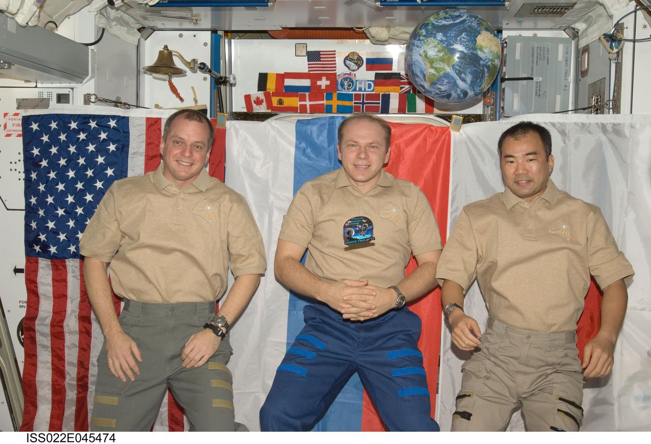 ISS022-E-045474 (31 Jan. 2010) --- NASA astronaut T.J. Creamer (left), Russian cosmonaut Oleg Kotov and Japan Aerospace Exploration Agency (JAXA) astronaut Soichi Noguchi, all Expedition 22 flight engineers, pose for a photo near the Soyuz TMA-17 patch floating freely in the Harmony node of the International Space Station.