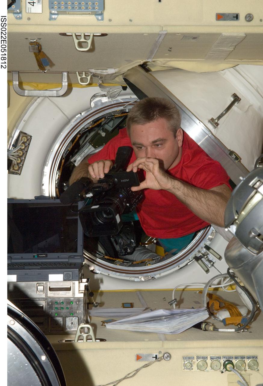ISS022-E-051812 (28 Jan. 2010) --- Russian cosmonaut Maxim Suraev, Expedition 22 flight engineer, uses a High Definition Video (HDV) camera in the in the Zvezda Service Module transfer compartment of the International Space Station.