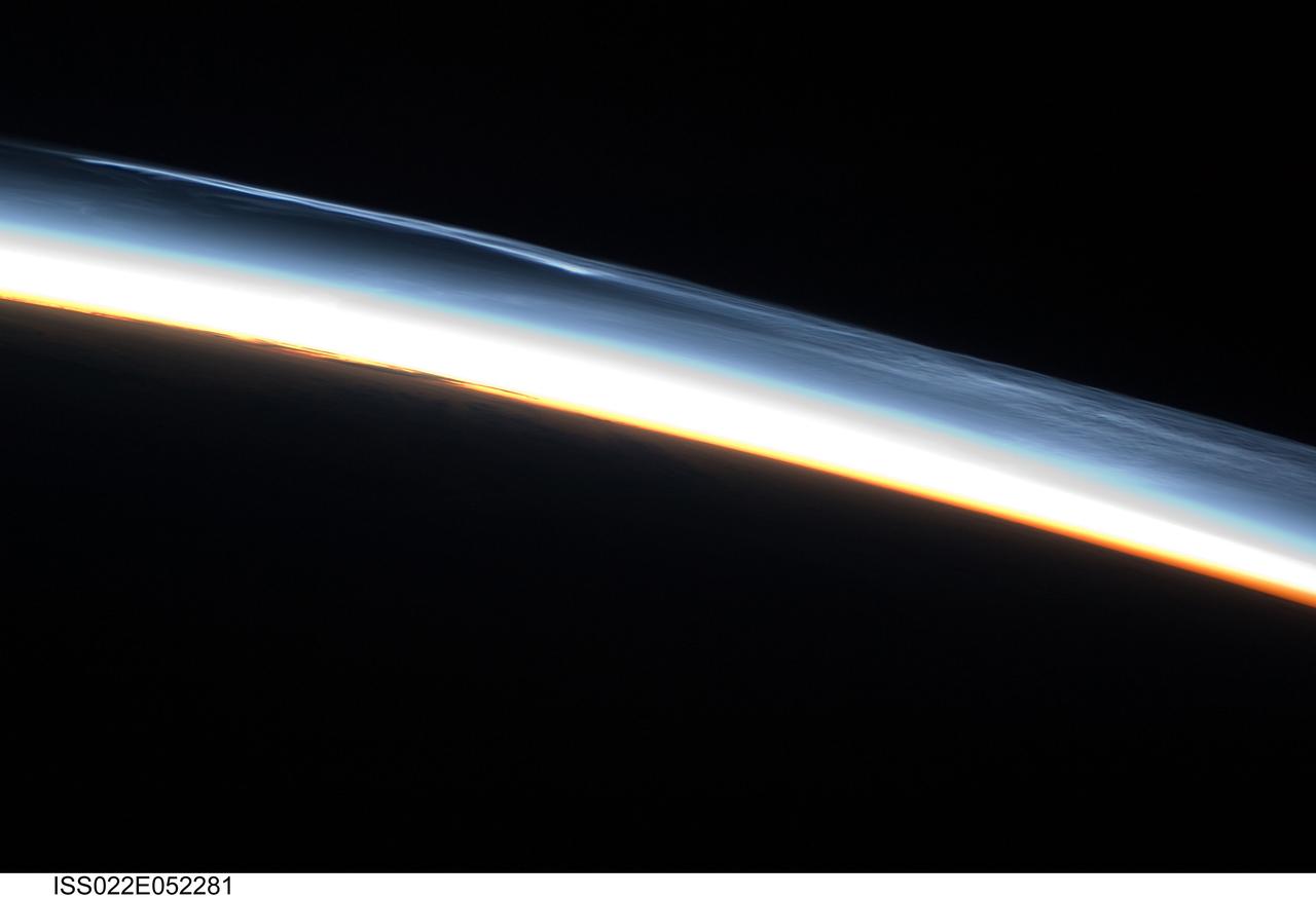 ISS022-E-052281 (30 Jan. 2010) --- Polar mesospheric clouds over the Southern Hemisphere are featured in this image photographed by an Expedition 22 crew member on the International Space Station. This striking view shows polar mesospheric clouds (PMC) over the polar region of the Southern Hemisphere. These clouds occur over the high latitudes of both northern and southern hemispheres during their respective summer months at very high altitudes of approximately 76?85 kilometers. When present they are visible during twilight, when the clouds are illuminated by the sun while the ground surface below is in darkness. The International Space Station (ISS) orbit extends from latitude 52 North to latitude 52 South; combined with the highly oblique views through Earth?s atmosphere possible with hand-held imagery, the ISS is an ideal platform for documenting these transient, high altitude phenomena. Another NASA mission, the Aeronomy of Ice in the Mesosphere or AIM satellite, is dedicated to the study of PMC and is providing daily information about their formation, distribution, and variability. Polar mesospheric clouds are also known as noctilucent or night-shining clouds ? a property that is clearly visible in this photograph. The PMC exhibit thin, wispy light blue forms that contrast with the darkness of space above (upper right). Lower levels of cloud are strongly illuminated by the sun and appear light orange to white. Clouds closest to Earth?s surface are reddish-orange (center). The image was taken approximately 38 minutes after midnight Greenwich Mean Time (GMT) while the ISS was located over the southern Atlantic Ocean. At this time of year, the sun never sets over Antarctica but rather defines an arc across the local horizon, allowing PMC to be observed near local midnight.