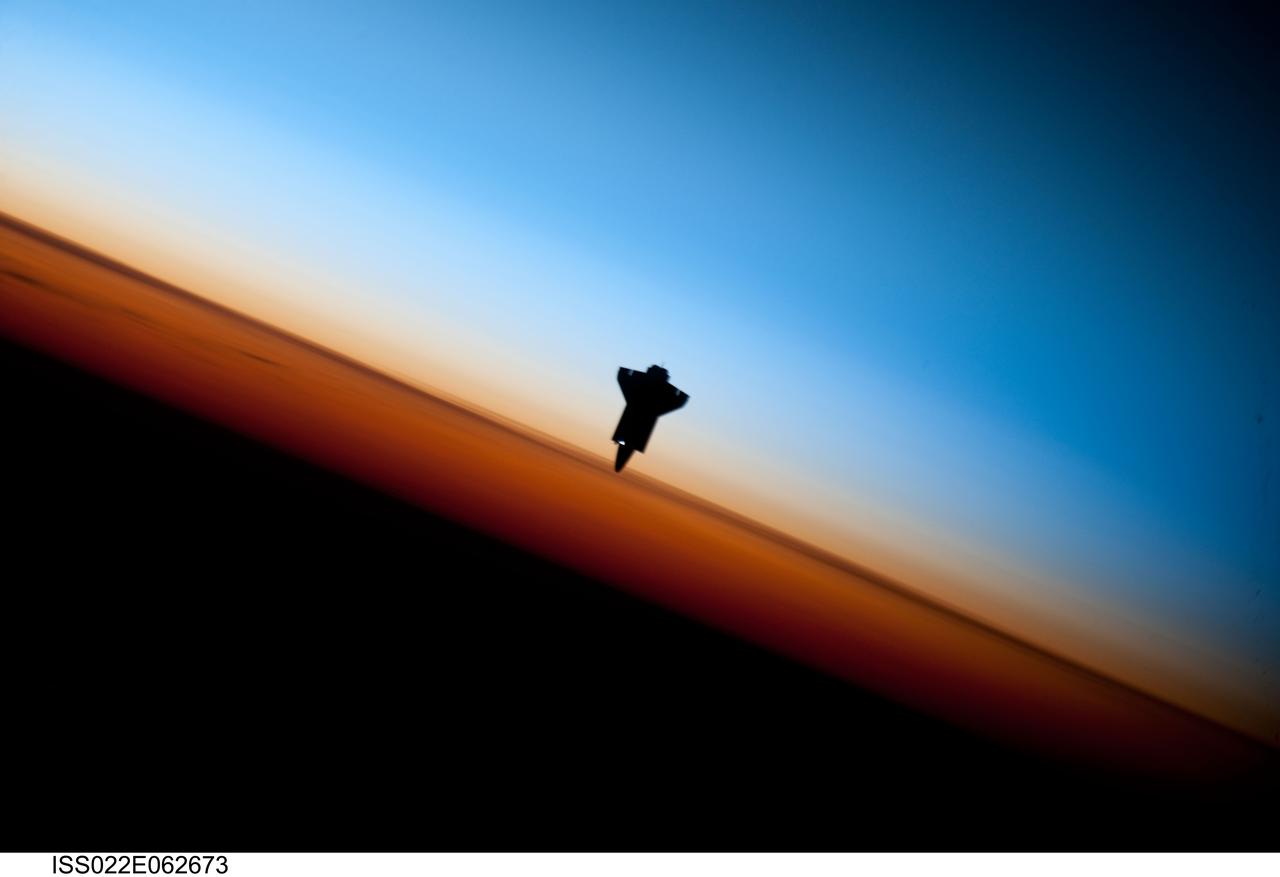 ISS022-E-062673 (9 Feb. 2010) --- Though astronauts and cosmonauts often encounter striking scenes of Earth's limb, this very unique image, part of a series over Earth's colorful horizon, has the added feature of a silhouette of the space shuttle Endeavour. The image was photographed by an Expedition 22 crew member prior to STS-130 rendezvous and docking operations with the International Space Station. Docking occurred at 11:06 p.m. (CST) on Feb. 9, 2010. The orbital outpost was at 46.9 south latitude and 80.5 west longitude, over the South Pacific Ocean off the coast of southern Chile with an altitude of 183 nautical miles when the image was recorded. The orange layer is the troposphere, where all of the weather and clouds which we typically watch and experience are generated and contained. This orange layer gives way to the whitish Stratosphere and then into the Mesosphere. In some frames the black color is part of a window frame rather than the blackness of space.