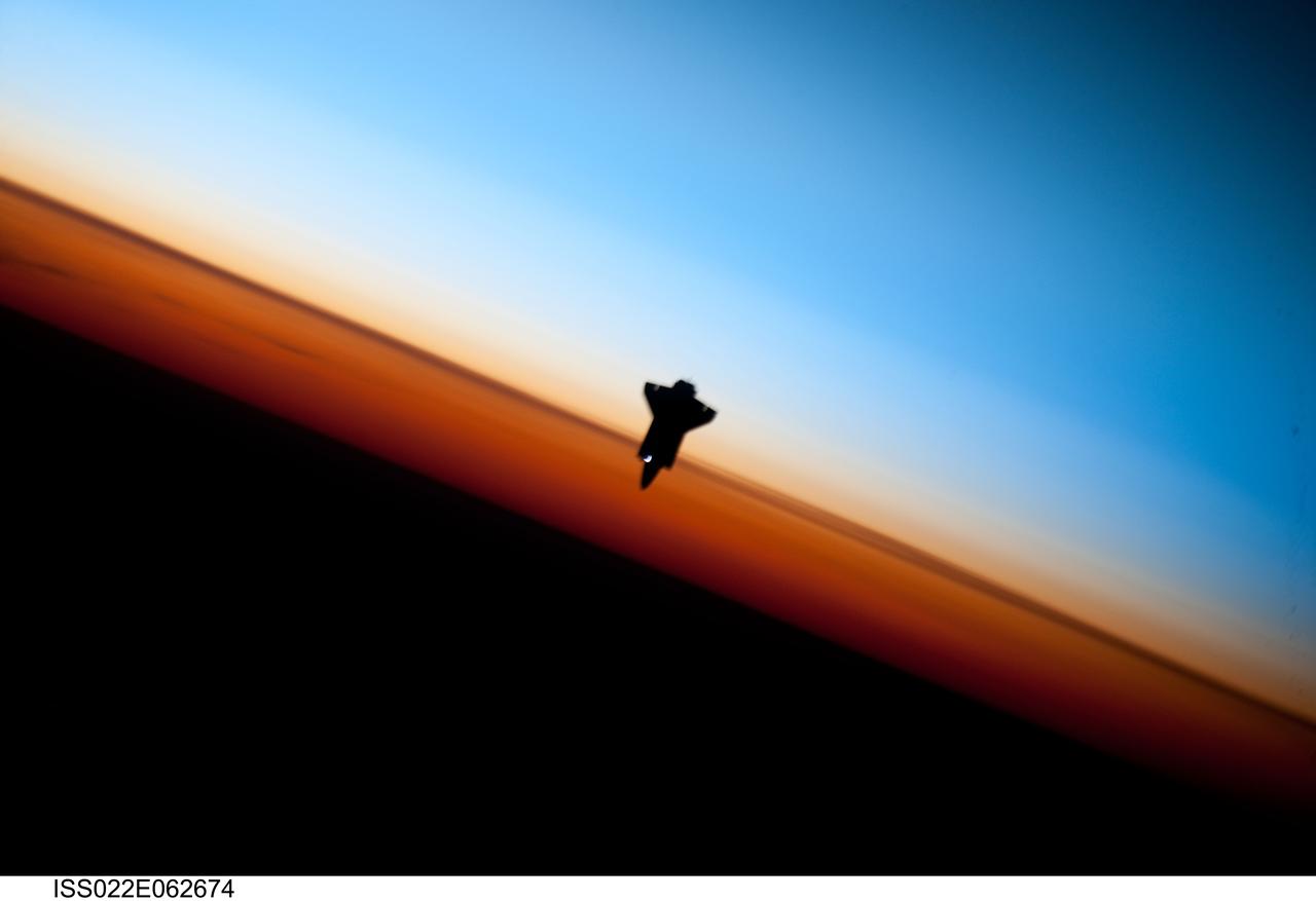 ISS022-E-062674 (9 Feb. 2010) --- Though astronauts and cosmonauts often encounter striking scenes of Earth's limb, this very unique image, part of a series over Earth's colorful horizon, has the added feature of a silhouette of the space shuttle Endeavour. The image was photographed by an Expedition 22 crew member prior to STS-130 rendezvous and docking operations with the International Space Station. Docking occurred at 11:06 p.m. (CST) on Feb. 9, 2010. The orbital outpost was at 46.9 south latitude and 80.5 west longitude, over the South Pacific Ocean off the coast of southern Chile with an altitude of 183 nautical miles when the image was recorded. The orange layer is the troposphere, where all of the weather and clouds which we typically watch and experience are generated and contained. This orange layer gives way to the whitish Stratosphere and then into the Mesosphere. In some frames the black color is part of a window frame rather than the blackness of space.