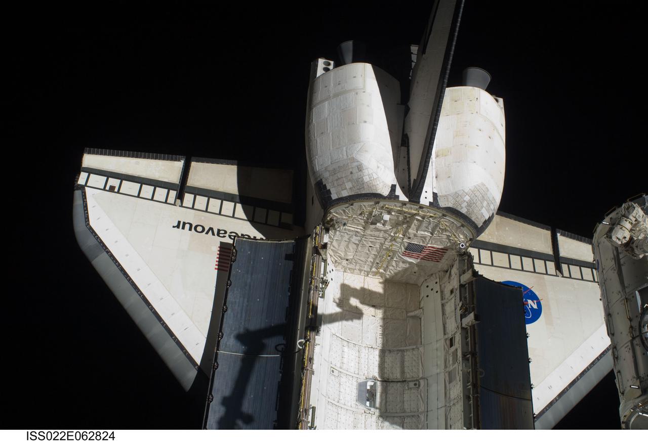 ISS022-E-062824 (11 Feb. 2010) --- Space shuttle Endeavour?s aft payload bay, orbital maneuvering system (OMS) pods, vertical stabilizer and wings are featured in this image photographed by an Expedition 22 crew member during the transfer of the Tranquility node (mostly out of frame at right) from its stowage position in Endeavour's (STS-130) payload bay to position it on the port side of the Unity node of the International Space Station. The shadow of Tranquility in the grasp of the Canadarm2 is visible on the shuttle.