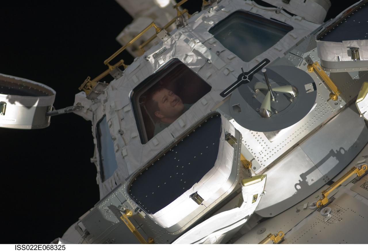 ISS022-E-068325 (18 Feb. 2010) --- NASA astronaut Nicholas Patrick, STS-130 mission specialist, is pictured in a window of the newly-installed Cupola of the International Space Station while space shuttle Endeavour remains docked with the station.