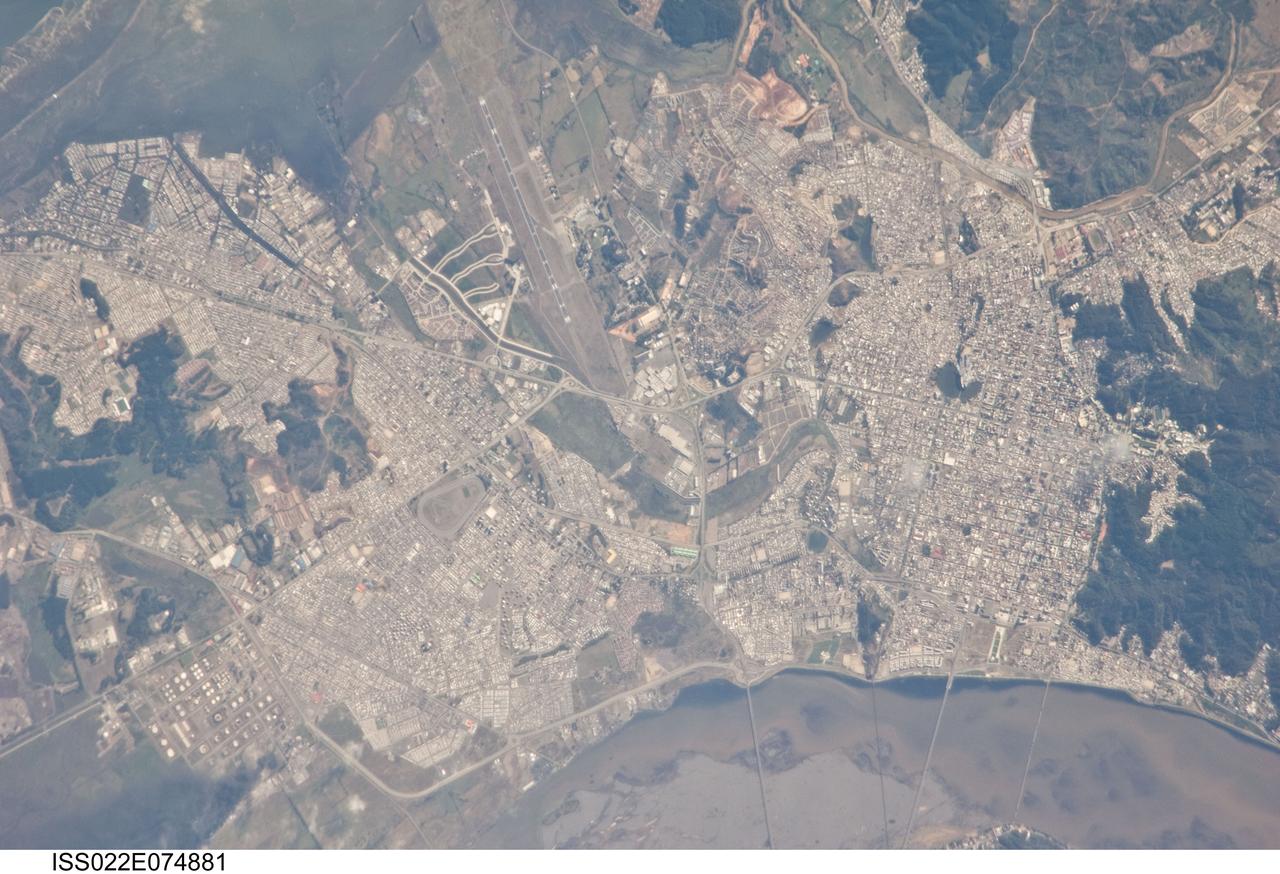 ISS022-E-074881 (27 Feb. 2010) --- Earthquake damage in Concepcion, Chile is featured in this image photographed by an Expedition 22 crew member on the International Space Station. This detailed view of the Chilean cities of Concepcion and Hualpen was acquired from the space station approximately seven hours after a magnitude 8.8 earthquake occurred offshore 115 kilometers to the north-northeast. Much of the Chilean coastline is located above the boundary between the converging Nazca and South American tectonic plates. This type of plate boundary is known as a subduction zone; such zones frequently experience moderate to strong earthquakes as one tectonic plate overrides the other. The largest earthquake worldwide during the past 200 years (magnitude 9.5 in May 1960) had a source region approximately 230 kilometers north of the Feb. 27 quake. While the image is not detailed enough to see damage to individual buildings or roadways some indicators of earthquake damage are visible. A dark smoke plume is visible at lower left near an oil refinery in Hualpen. At lower right, parts of the road bed of a single-lane bridge over the Bio-Bio River appear to have collapsed. A smaller, white smoke plume is visible at right near the Universidad de Concepcion. Smoke and haze possibly related to the earthquake was noted over Santiago, Chile in data acquired by the MODIS sensor less than one hour after this photograph was taken.