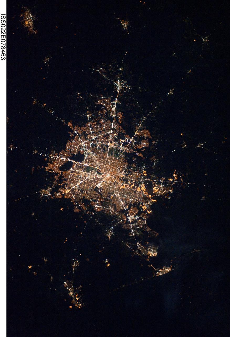ISS022-E-078463 (28 Feb. 2010) ---The Houston metropolitan area at night is featured in this image photographed by an Expedition 22 crew member on the International Space Station. Houston, Texas has been called the ?energy capital of the world? due to its role as a major hub of the petroleum and other energy resource industries. The image is oriented with north toward the top. The Houston metropolitan area covers almost 2,331,000 hectares (approximately 9,000 square miles) along the southeast Texas coastline, with an average elevation of 13 meters (approximately 43 feet) above sea level and a population of over 5 million (2006 US Census estimate). The Houston metropolitan area is also noteworthy as being the largest in the US without formal zoning restrictions. This has lead to a highly diverse pattern of land use at the neighborhood scale; nevertheless, more general spatial patterns of land use can be recognized in remotely sensed data. This is particularly evident in night time photography of the urban area taken by crew members onboard the space station. The image depicts the roughly 100 kilometers (approximately 62 miles) east-west extent of the Houston metropolitan area. Houston proper is at center, indicated by a ?bull?s-eye? of elliptical white to orange-lighted beltways and brightly lit white freeways radiating outwards from the central downtown area. Suburban and primarily residential urban land use is indicated by both reddish-brown and gray-green lighted regions that reflect a higher proportion of tree cover and lower light density. Petroleum refineries along the Houston Ship Channel are recognized by densely lit areas of golden yellow light. Rural and undeveloped land circles the metropolitan area, and Galveston Bay to the southeast (lower right) provides access to the Gulf of Mexico. Both types of non-urban surface appear dark in the image.