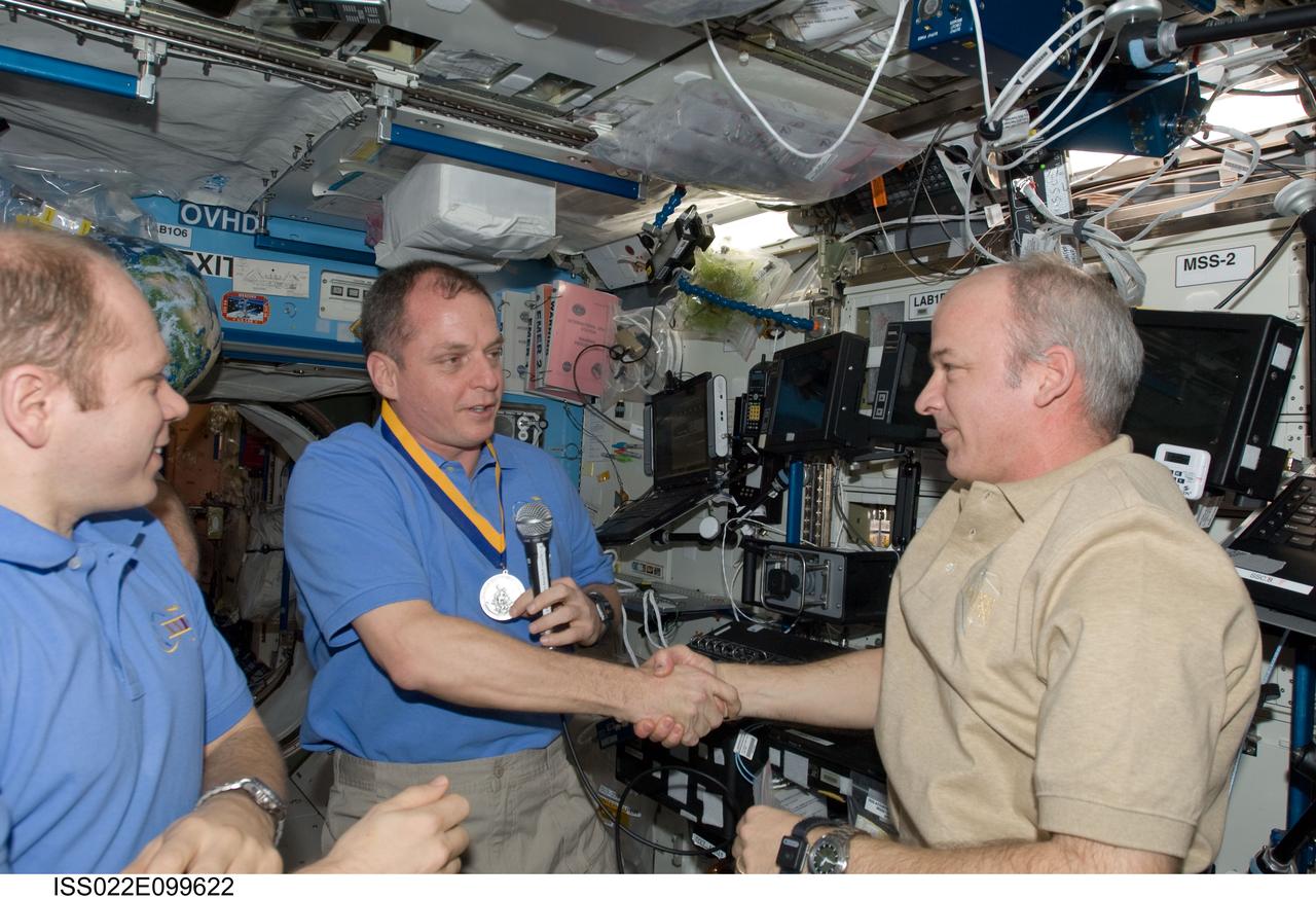 ISS022-E-099622 (17 March 2010) --- NASA astronaut Jeffrey Williams (right), Expedition 22 commander, presents the Army aviator award of St. Michael to fellow Army officer T.J. Creamer (center), Expedition 22/23 flight engineer, prior to the start of the ceremony of Changing-of-Command from Expedition 22 to Expedition 23. Russian cosmonaut Oleg Kotov, Expedition 22 flight engineer and Expedition 23 commander, is at left.