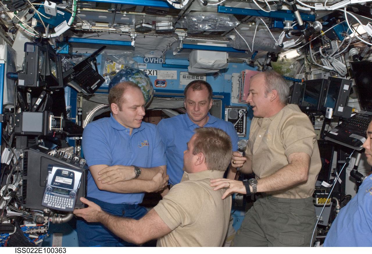 ISS022-E-100363 (17 March 2010) --- Crew members aboard the International Space Station are pictured in the Destiny laboratory during the ceremony of Changing-of-Command from Expedition 22 to Expedition 23. Pictured are NASA astronauts Jeffrey Williams (right, holding microphone), Expedition 22 commander; and T.J. Creamer (center background), Expedition 22/23 flight engineer; Russian cosmonauts Oleg Kotov (left), Expedition 22 flight engineer and Expedition 23 commander; and Maxim Suraev (bottom), Expedition 22 flight engineer; along with Japan Aerospace Exploration Agency (JAXA) astronaut Soichi Noguchi (mostly out of frame at right), Expedition 22/23 flight engineer.