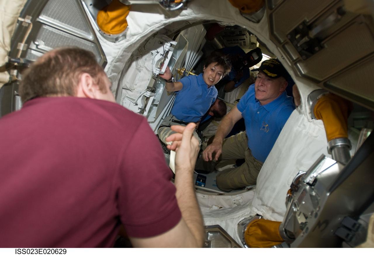 ISS023-E-020629 (7 April 2010) --- Russian cosmonaut Oleg Kotov (far left), Expedition 23 commander, prepares to greet the STS-131 crew as it comes aboard the International Space Station to spend several days in a number of busy joint activities for the two crews. Seen clearly in the hatch are astronaut Alan Poindexter, STS-131 commander, and Japan Aerospace Agency astronaut Naoko Yamazaki, mission specialist.
