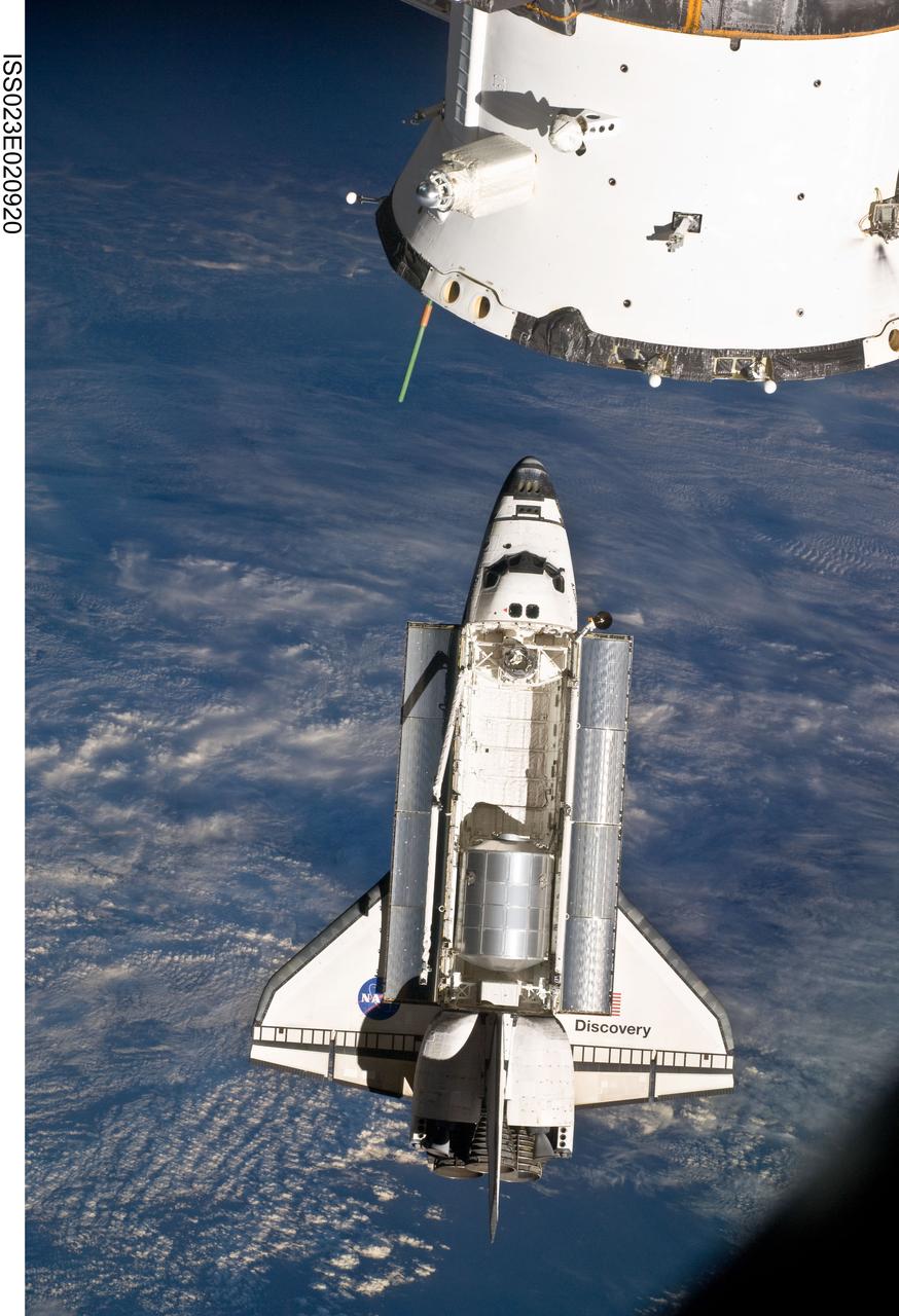 ISS023-E-020920 (7 April 2010) --- The space shuttle Discovery and the International Space Station are in the midst of their rendezvous and docking activities in this image photographed by an Expedition 23 crew member aboard the orbital outpost. Part of a docked Russian spacecraft can be seen in the foreground.