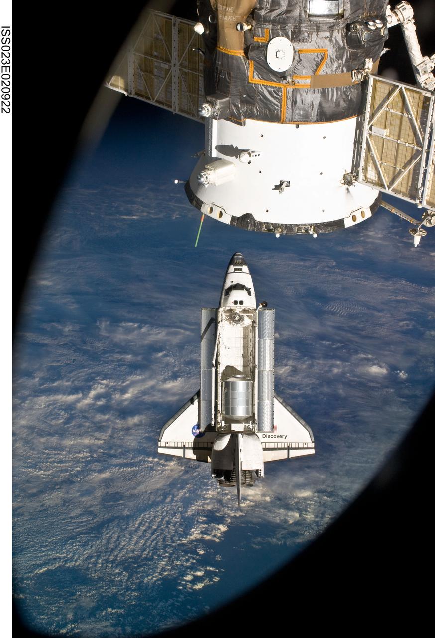 ISS023-E-020922 (7 April 2010) --- The space shuttle Discovery and the International Space Station are in the midst of their rendezvous and docking activities in this image photographed by an Expedition 23 crew member aboard the orbital outpost. Part of a docked Russian spacecraft can be seen in the foreground.
