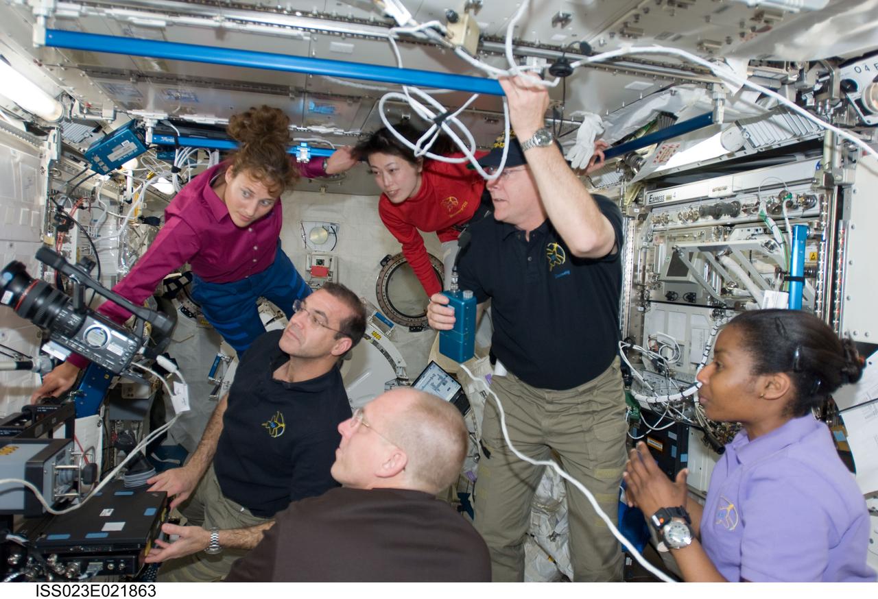 ISS023-E-021863 (11 April 2010) --- STS-131 crew members gather in the Kibo laboratory of the International Space Station for a teleconference while space shuttle Discovery remains docked with the station. NASA astronaut Alan Poindexter, commander, holds a communication system at right center. Also pictured (clockwise from bottom right) are NASA astronauts Stephanie Wilson, Clayton Anderson, Rick Mastracchio and Dorothy Metcalf-Lindenburger; along with Japan Aerospace Exploration Agency (JAXA) astronaut Naoko Yamazaki, all mission specialists.