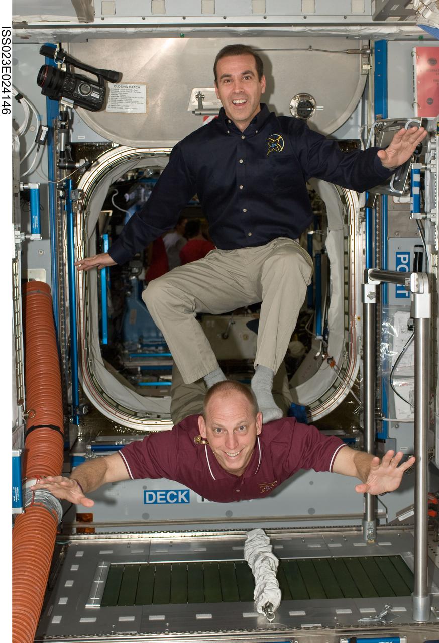 ISS023-E-024146 (16 April 2010) --- NASA astronauts Rick Mastracchio (top) and Clayton Anderson, both STS-131 mission specialists, pose for a photo near the Combined Operational Load Bearing External Resistance Treadmill (COLBERT) in the Harmony node of the International Space Station while space shuttle Discovery remains docked with the station.