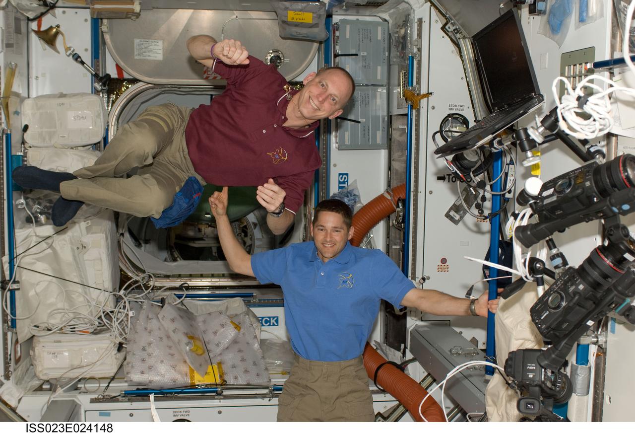 ISS023-E-024148 (16 April 2010) --- NASA astronauts James P. Dutton Jr. (bottom), STS-131 pilot; and Clayton Anderson, mission specialist, pose for a photo in the Harmony node of the International Space Station while space shuttle Discovery remains docked with the station.
