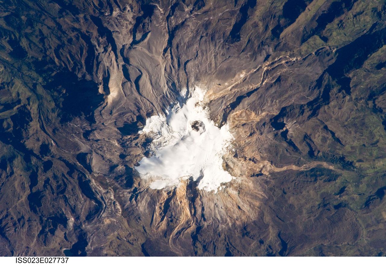 ISS023-E-027737 (23 April 2010) --- Nevado del Ruiz volcano in Colombia is featured in this image photographed by an Expedition 23 crew member on the International Space Station. The large Nevado del Ruiz volcano (center) is located approximately 140 kilometers to the northwest of the capital city of Bogota and covers an area of over 200 square kilometers. Nevado del Ruiz is a stratovolcano – a type of volcano built from successive layers of lava, ash, and pyroclastic flow deposits – formed by magma generated above the boundary between the subducting Nazca and overriding South American tectonic plates. The historical record of eruptions extends back to 1570, but the most damaging eruption in recent times took place in 1985. On Nov. 13, 1985, an explosive eruption at the Arenas Crater (center) melted ice and snow at the summit of the volcano. This lead to the formation of mudflows (or lahars) that swept tens of kilometers down river valleys along the volcano’s flanks, resulting in the deaths of at least 23,000 people. Most of the fatalities occurred in the town of Armero which was completely inundated by lahars. Eruptive activity at Nevado del Ruiz may have occurred in 1994, but this is not confirmed. The volcano’s summit and upper flanks are covered by several glaciers that appear as a white mass surrounding the one-kilometer-wide Arenas Crater; meltwater from these glaciers has incised the gray to tan ash and pyroclastic flow deposits mantling the lower slopes. A well-defined lava flow is visible at lower right. This photograph was taken at approximately 7:45 a.m. local time when the sun was still fairly low above the horizon, leading to shadowing to the west of topographic high points.