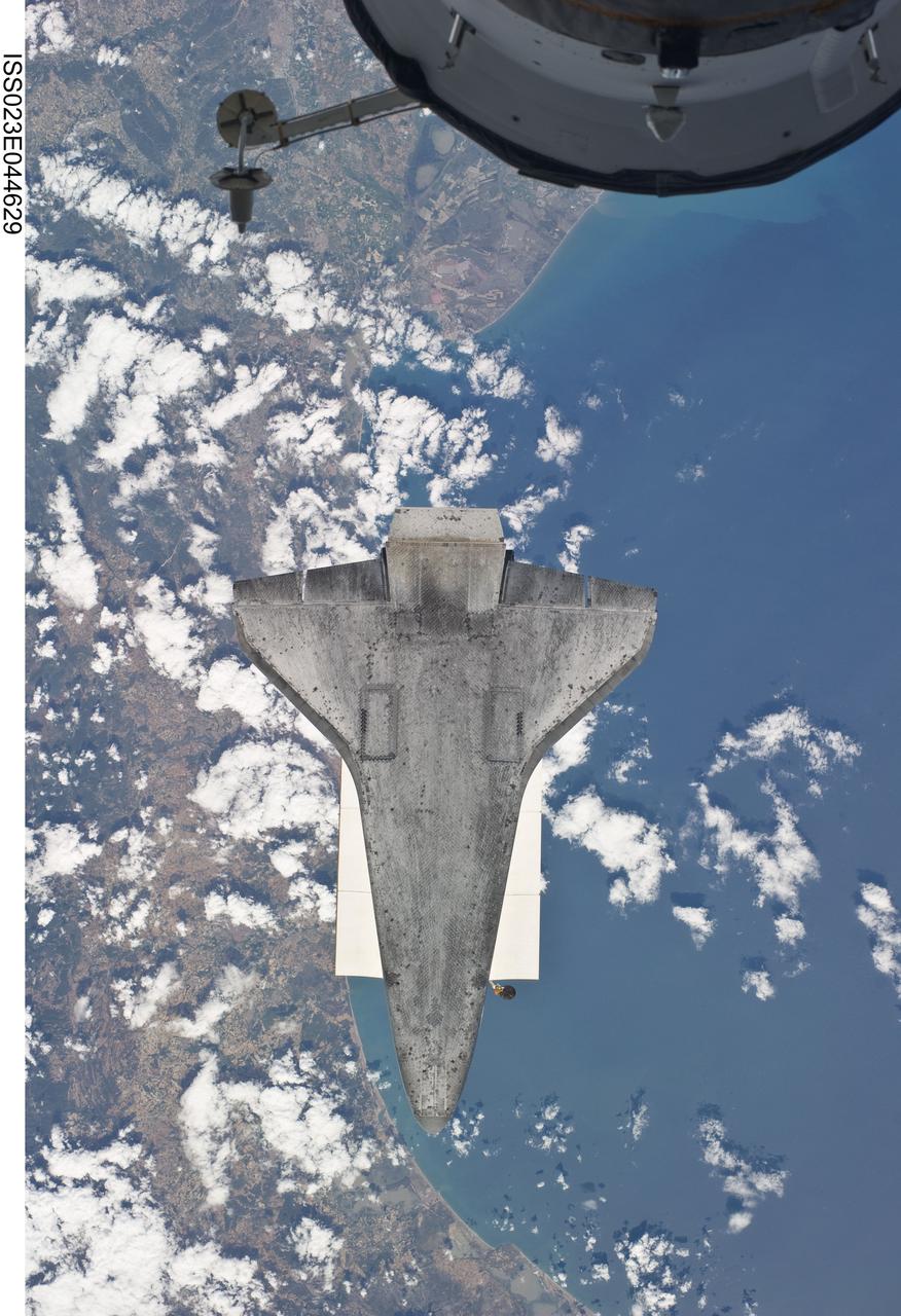 ISS023-E-044629 (16 May 2010) --- Backdropped by a colorful Earth, space shuttle Atlantis is featured in this image photographed by an Expedition 23 crew member as the shuttle approaches the International Space Station during STS-132 rendezvous and docking operations. Docking occurred at 9:28 a.m. (CDT) on May 16, 2010. A portion of a docked Russian spacecraft is visible at top.