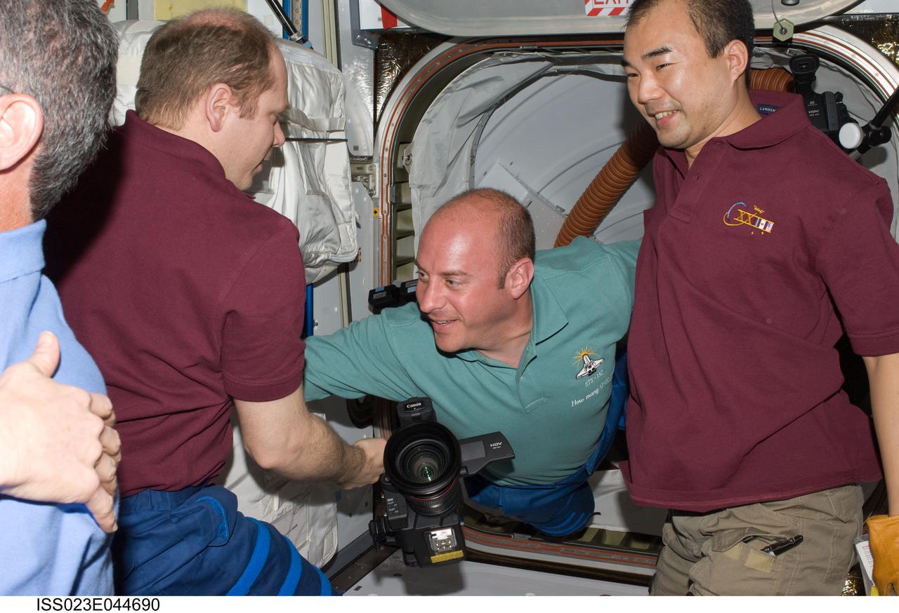 ISS023-E-044690 (16 May 2010) --- Soon after initial hatch opening, Expedition 23 crew members welcome the STS-132 crew aboard the International Space Station. Pictured are Russian cosmonaut Oleg Kotov (left), Expedition 23 commander; NASA astronaut Garrett Reisman (center), STS-132 mission specialist; and Japan Aerospace Exploration Agency (JAXA) astronaut Soichi Noguchi, Expedition 23 flight engineer.