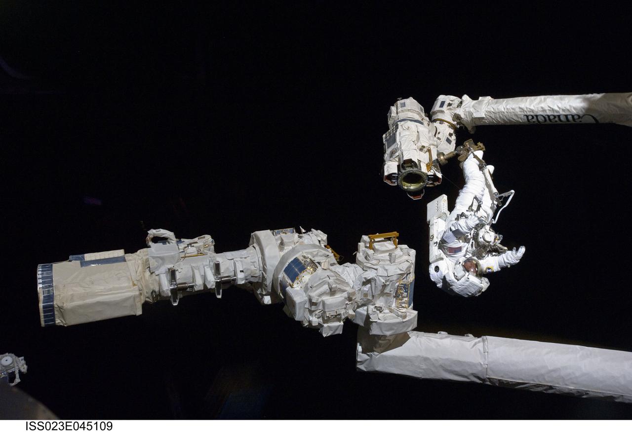 ISS023-E-045109 (17 May 2010) --- Anchored to a Canadarm2 mobile foot restraint, NASA astronaut Garrett Reisman, STS-132 mission specialist, participates in the mission's first session of extravehicular activity (EVA) as construction and maintenance continue on the International Space Station. During the seven-hour, 25-minute spacewalk, Reisman and NASA astronaut Steve Bowen (out of frame), mission specialist, loosened bolts holding six replacement batteries, installed a second antenna for high-speed Ku-band transmissions and adding a spare parts platform to Dextre, a two-armed extension for the station?s robotic arm.